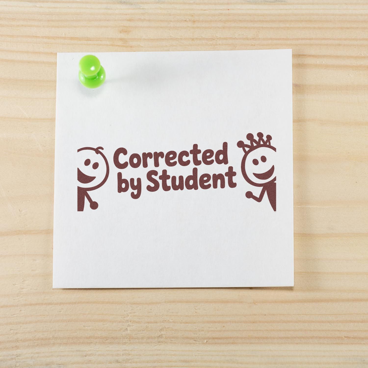 Brown Corrected by Student stamp with playful faces on white paper, pinned by a lime-green pushpin.