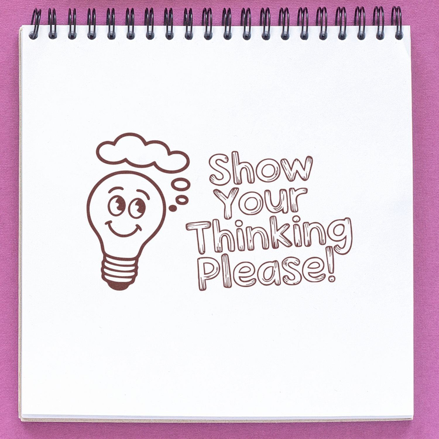 Brown stamp-style light bulb and Show Your Thinking Please! on a white spiral notepad with a purple background.