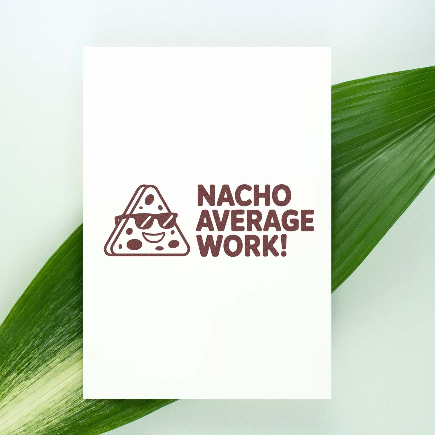 Brown rubber stamp seal reading NACHO AVERAGE WORK! with a sunglasses cheese slice on a white card.