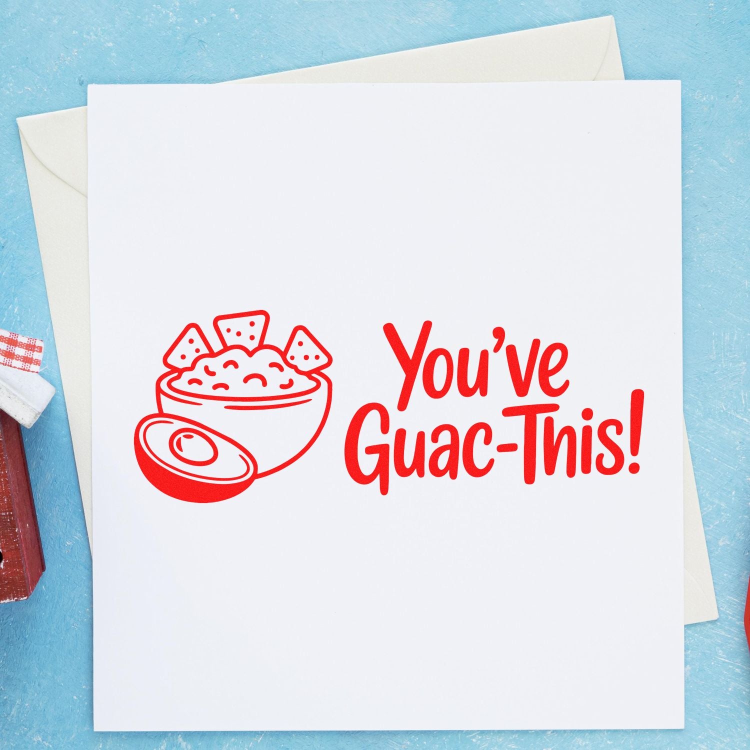 Red guacamole stamp and seal reading Youve Guac-This! on white card with blue background.