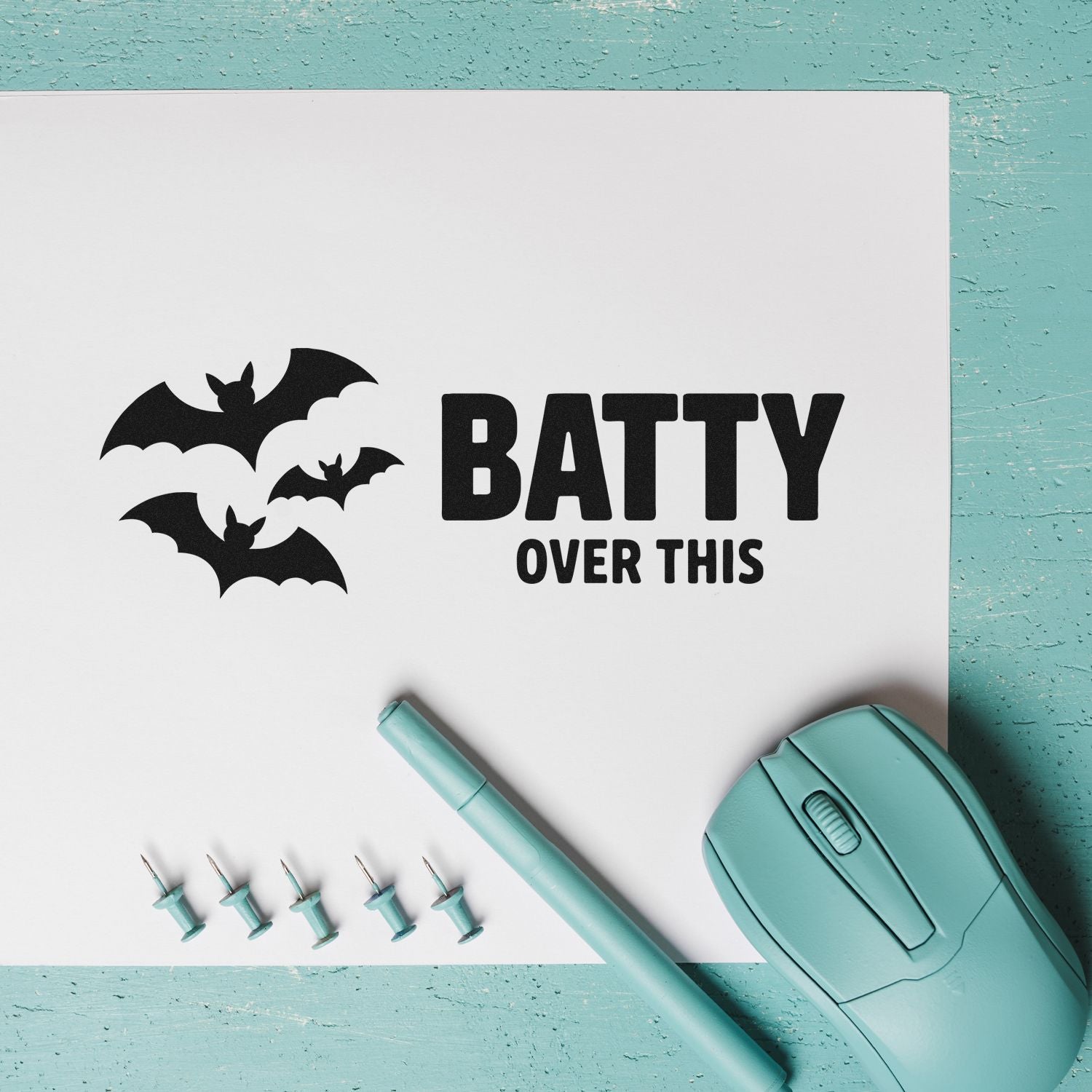 Bat-themed stamp and seal set with black BATTY OVER THIS text, teal embossing pen, pins, and aqua stamp tool.
