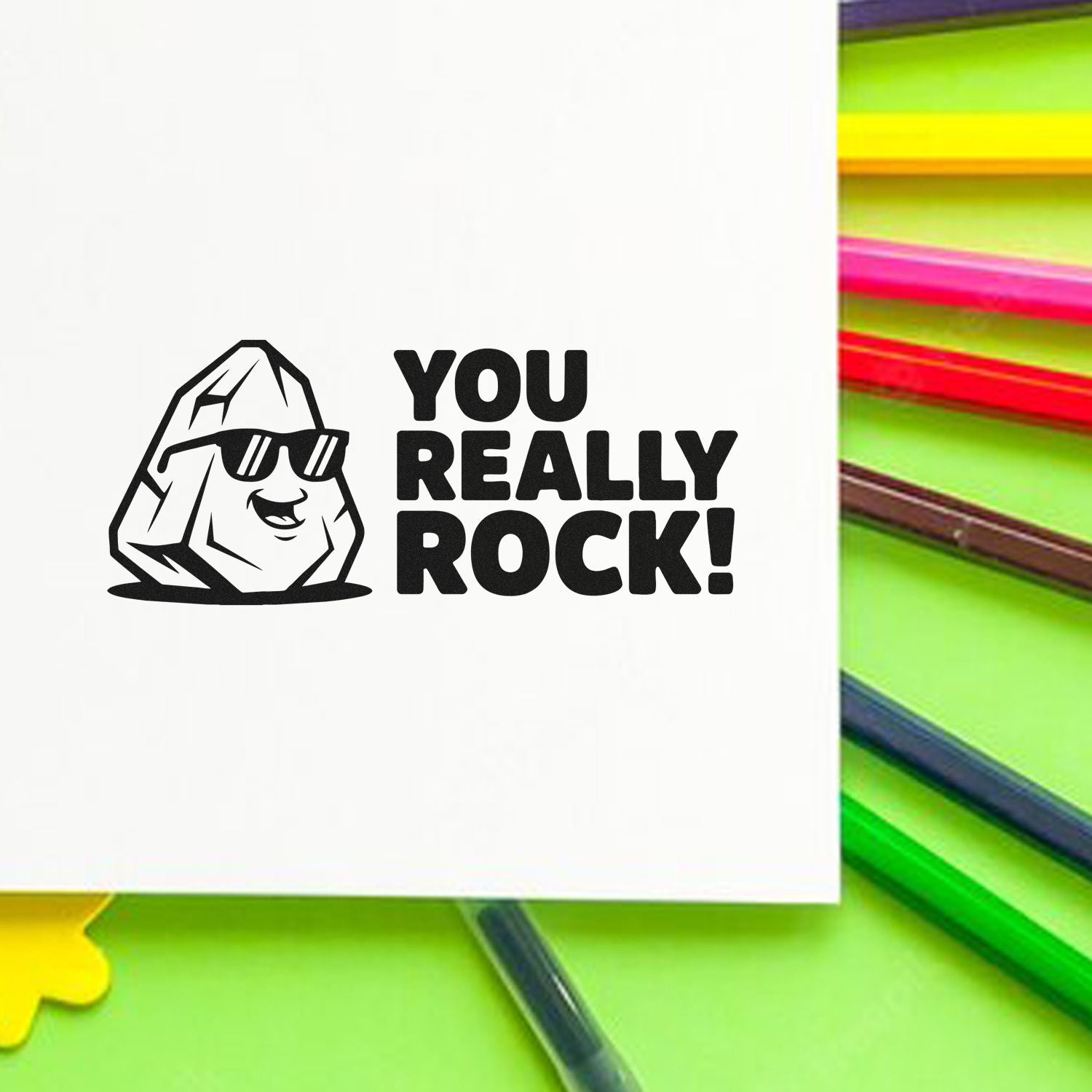 Black custom stamp/seal design with a rock in sunglasses and YOU REALLY ROCK! text on white, beside bright neon pencils.