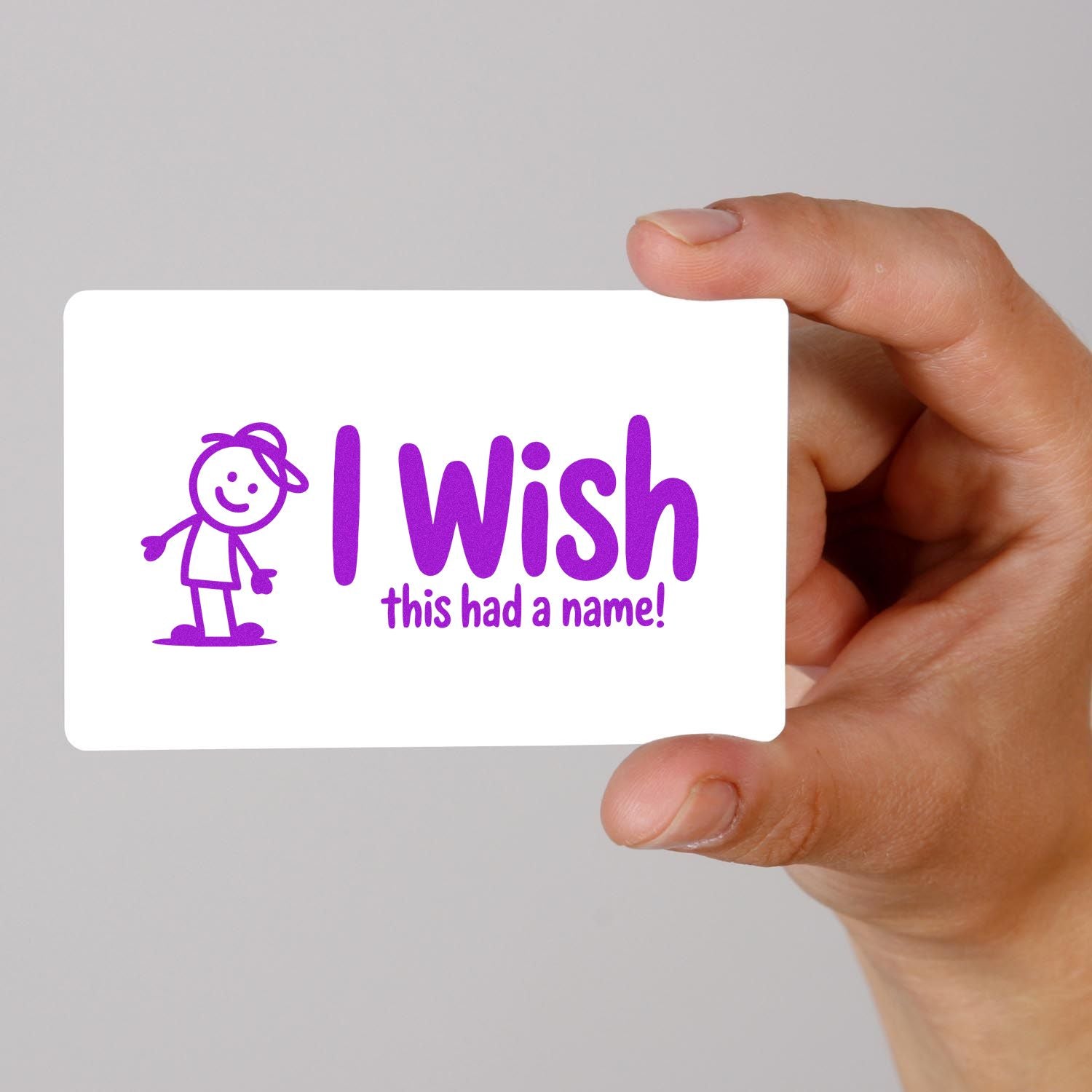 Purple stamp seal reading I wish this had a name! with cartoon figure on a white card, held by hand.