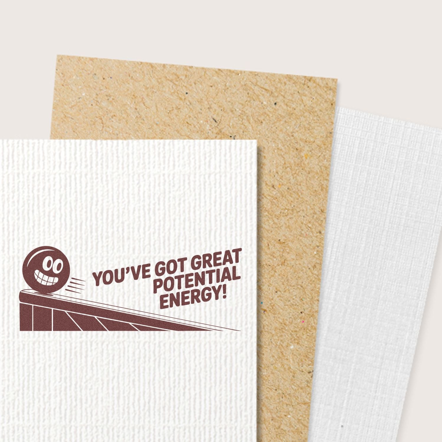 Brown motivational stamp on white textured card: smiling character and Youve got great potential energy! with kraft and white paper samples.