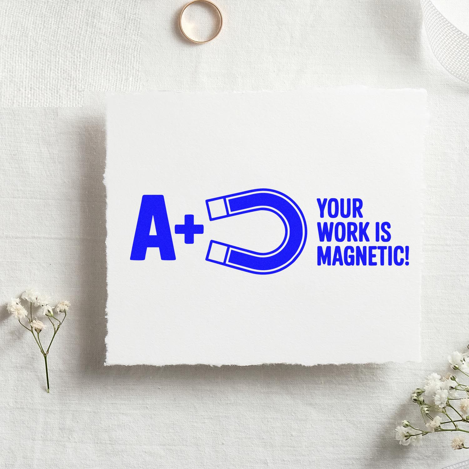 Blue custom stamp and seal design with A+ horseshoe magnet and Your work is magnetic! on white textured paper.