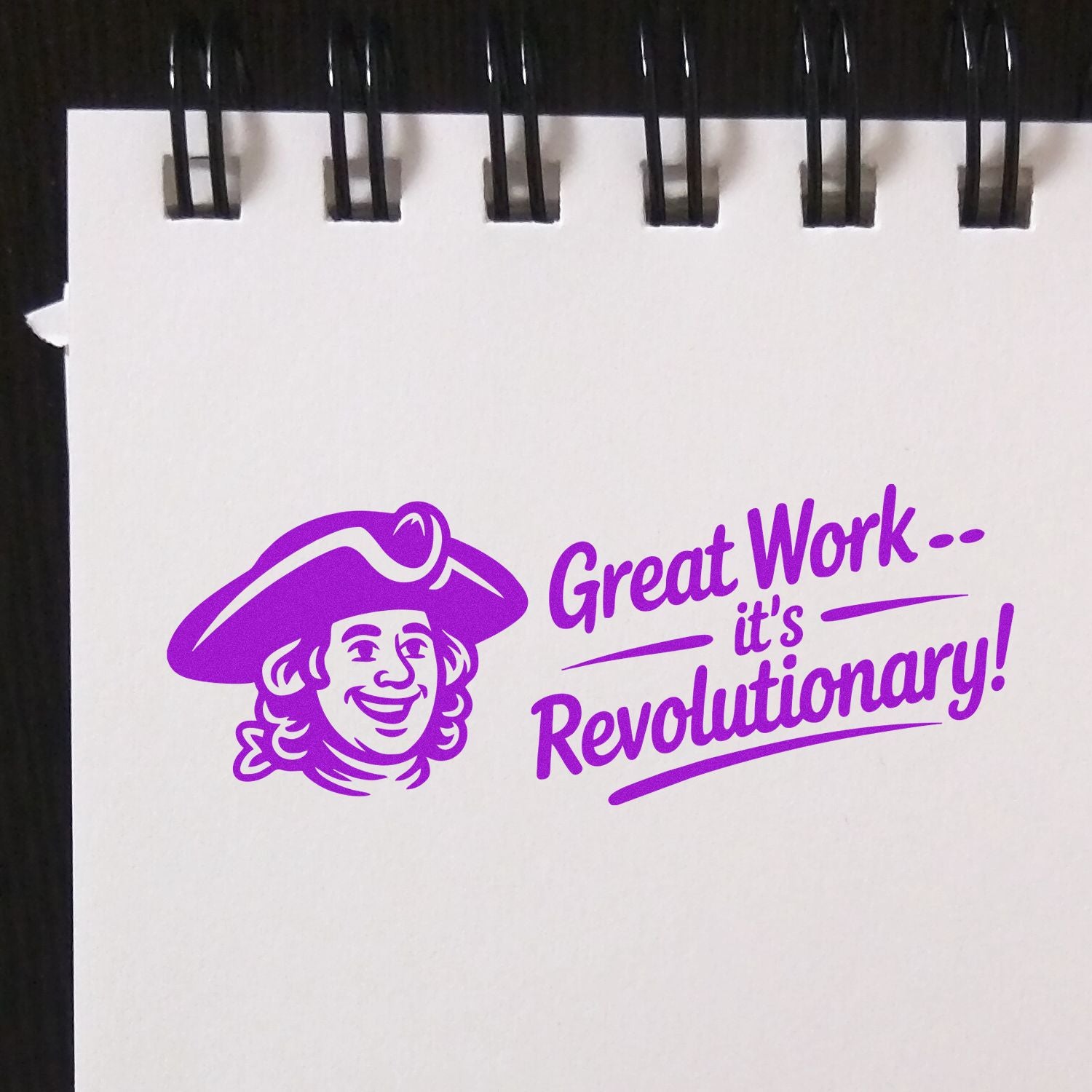 Purple stamp seal with smiling revolutionary mascot and Great Workits Revolutionary! on white notebook paper.