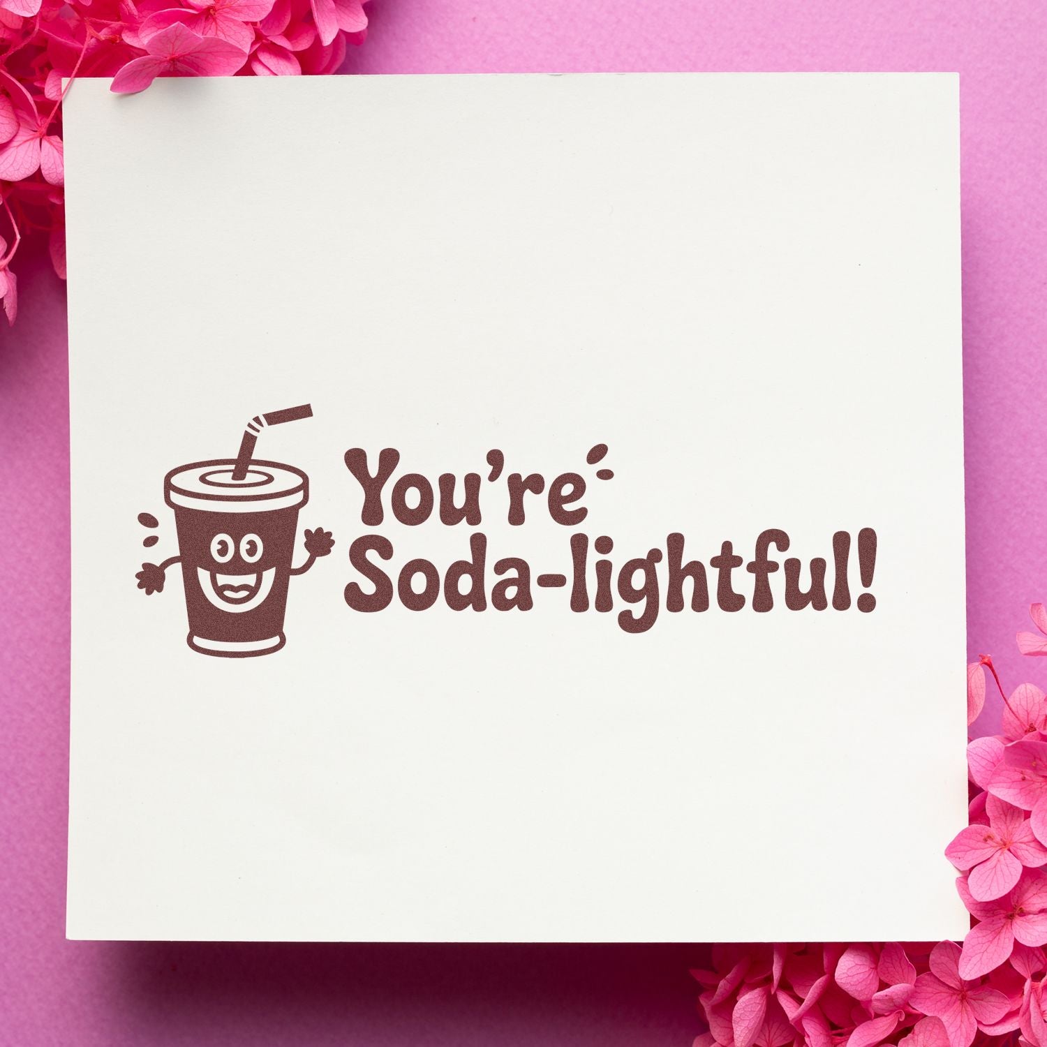 Brown soda cup stamp and seal with Youre Soda-lightful! on white paper, surrounded by bright pink flowers.