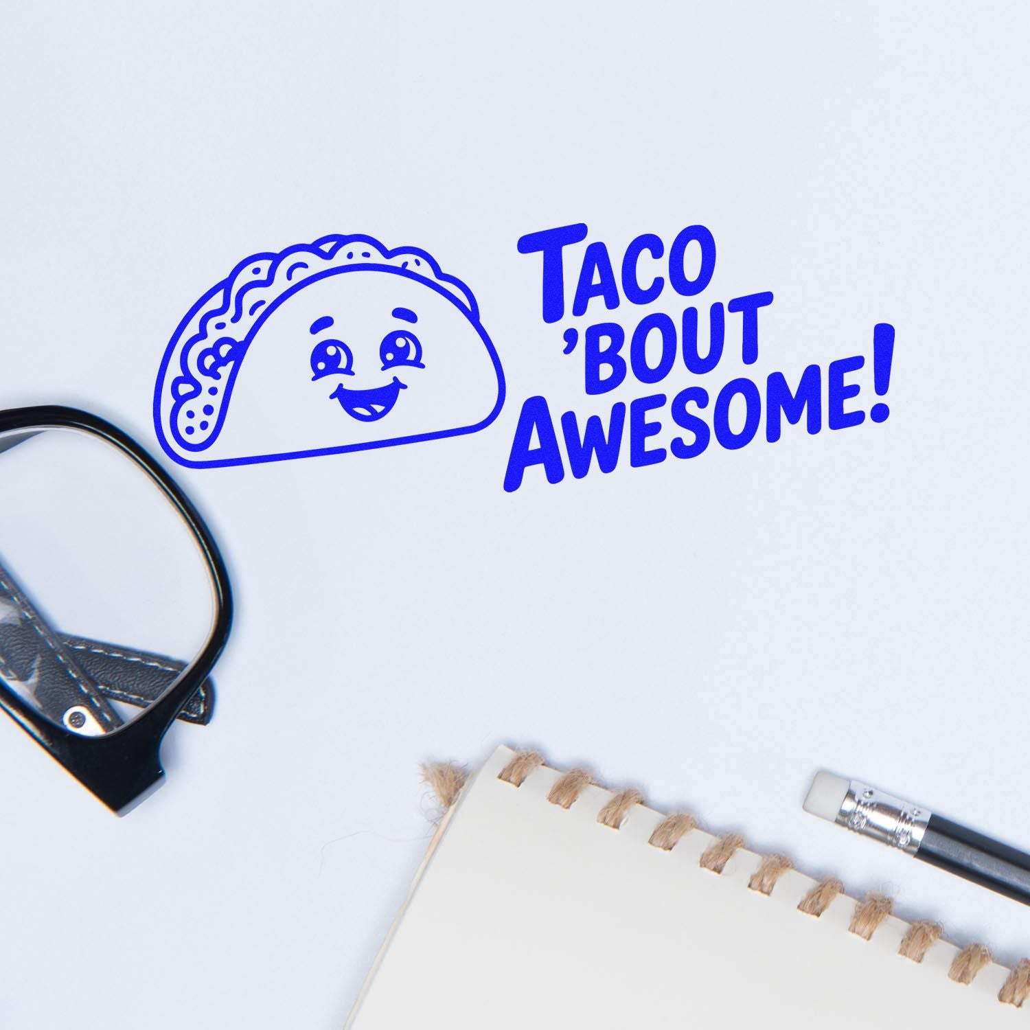 Blue taco stamp and seal reading Taco bout awesome! on white, with stationery and paper clips.