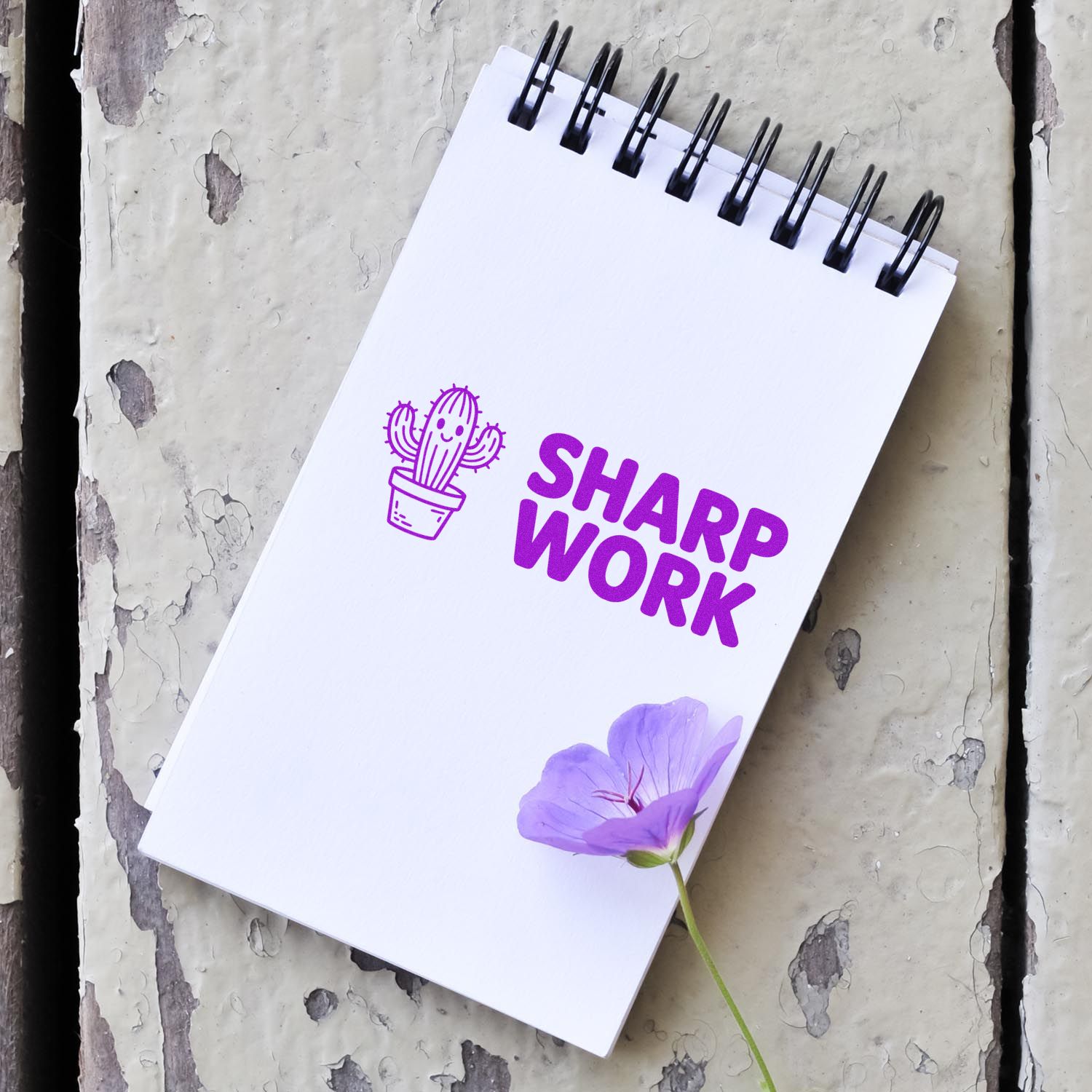 Purple SHARP WORK stamp and seal logo on a white spiral notebook with cactus icon and lavender flower.