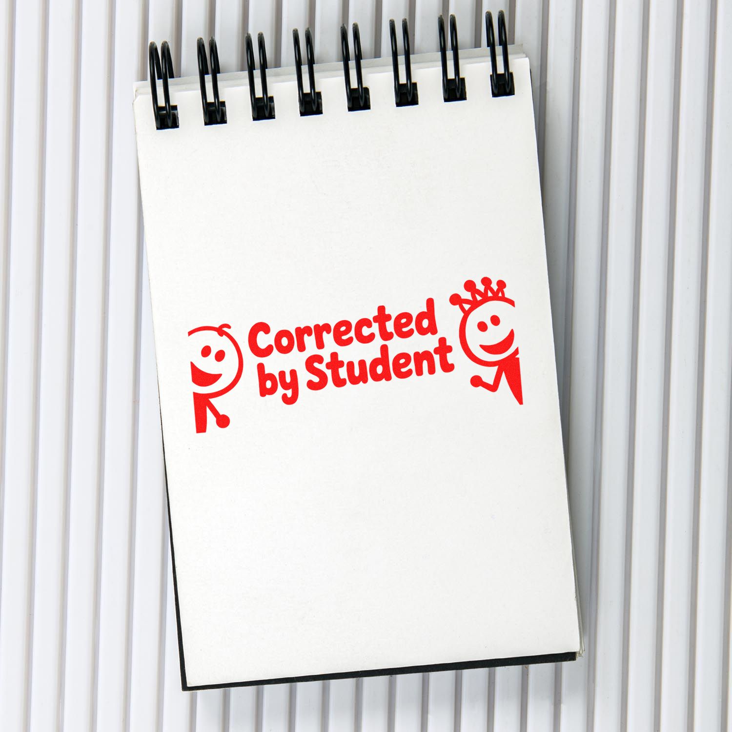 Red Corrected by Student stamp seal on a white spiral notepad with black binding, school grading product.