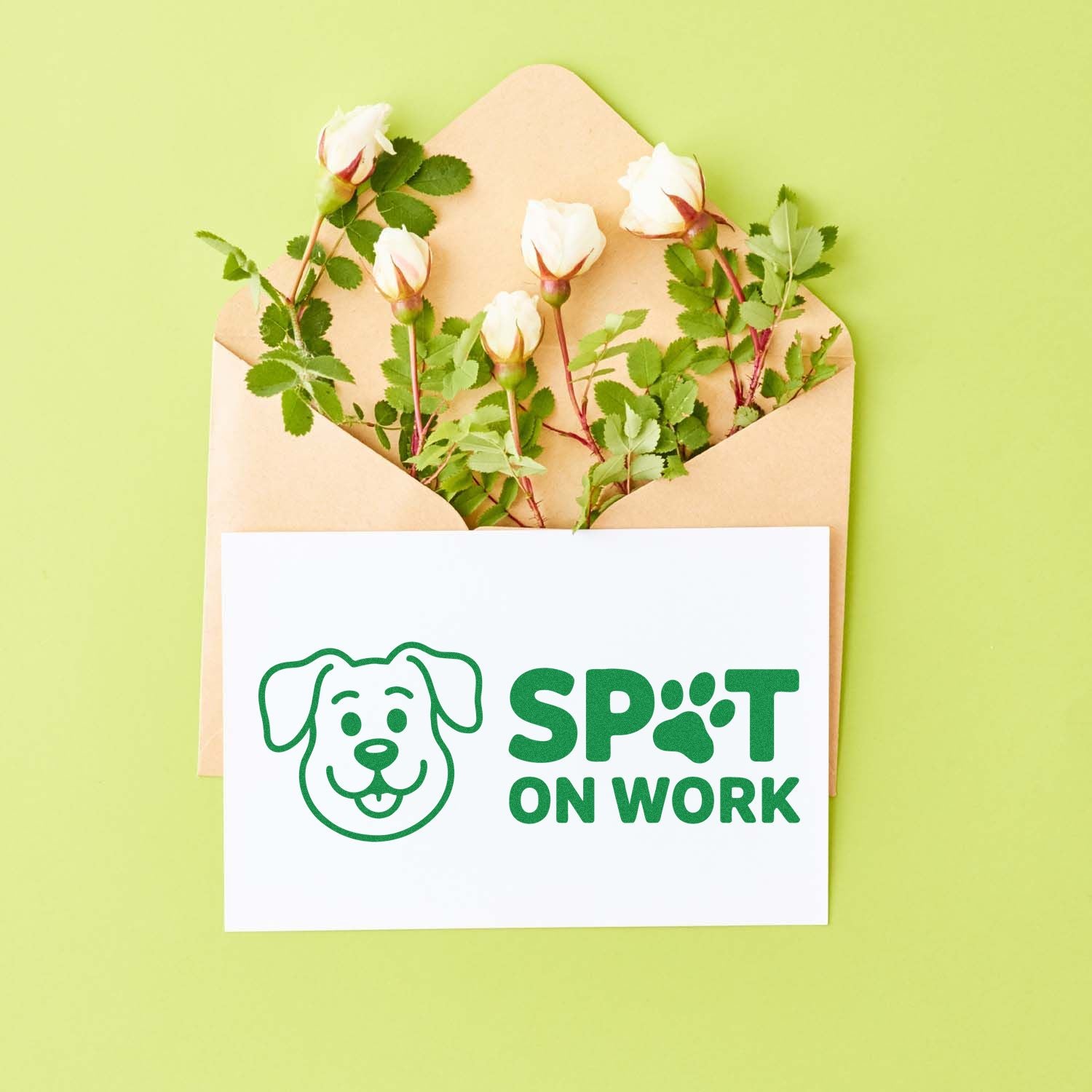 Green dog-logo stamp seal reading SPOT ON WORK on a white card, tucked in a tan envelope with white roses, on a lime background.