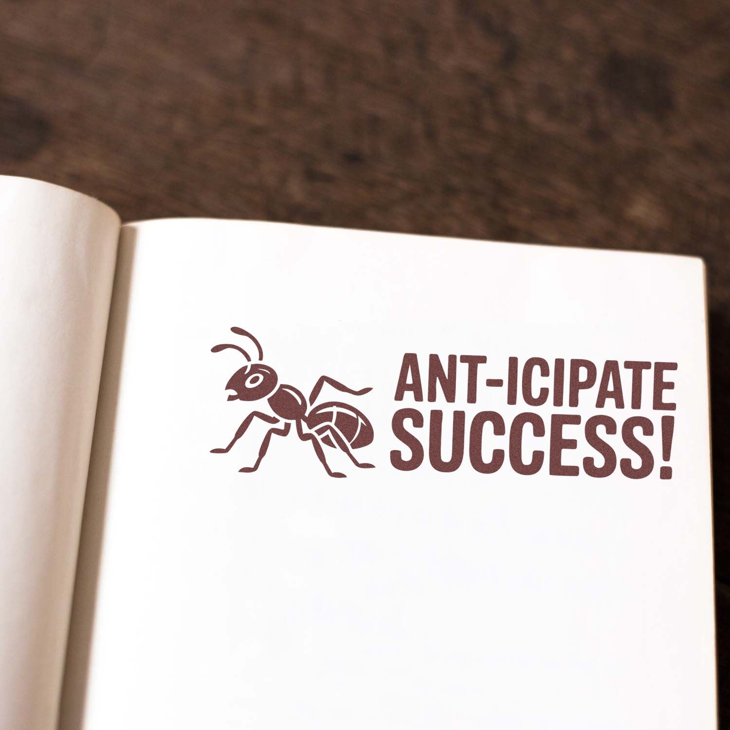 Brown ant stamp seal reading ANT-ICIPATE SUCCESS! on white paper