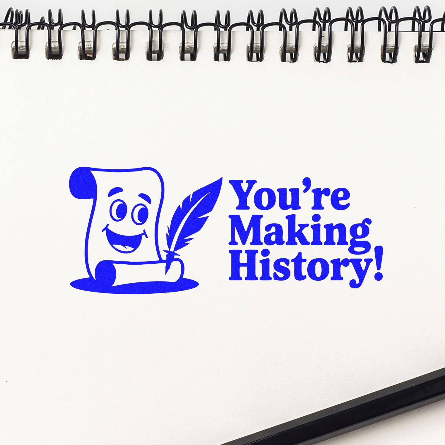 Blue stamp and seal design with smiling scroll and feather, reading Youre Making History! on white spiral-bound page.