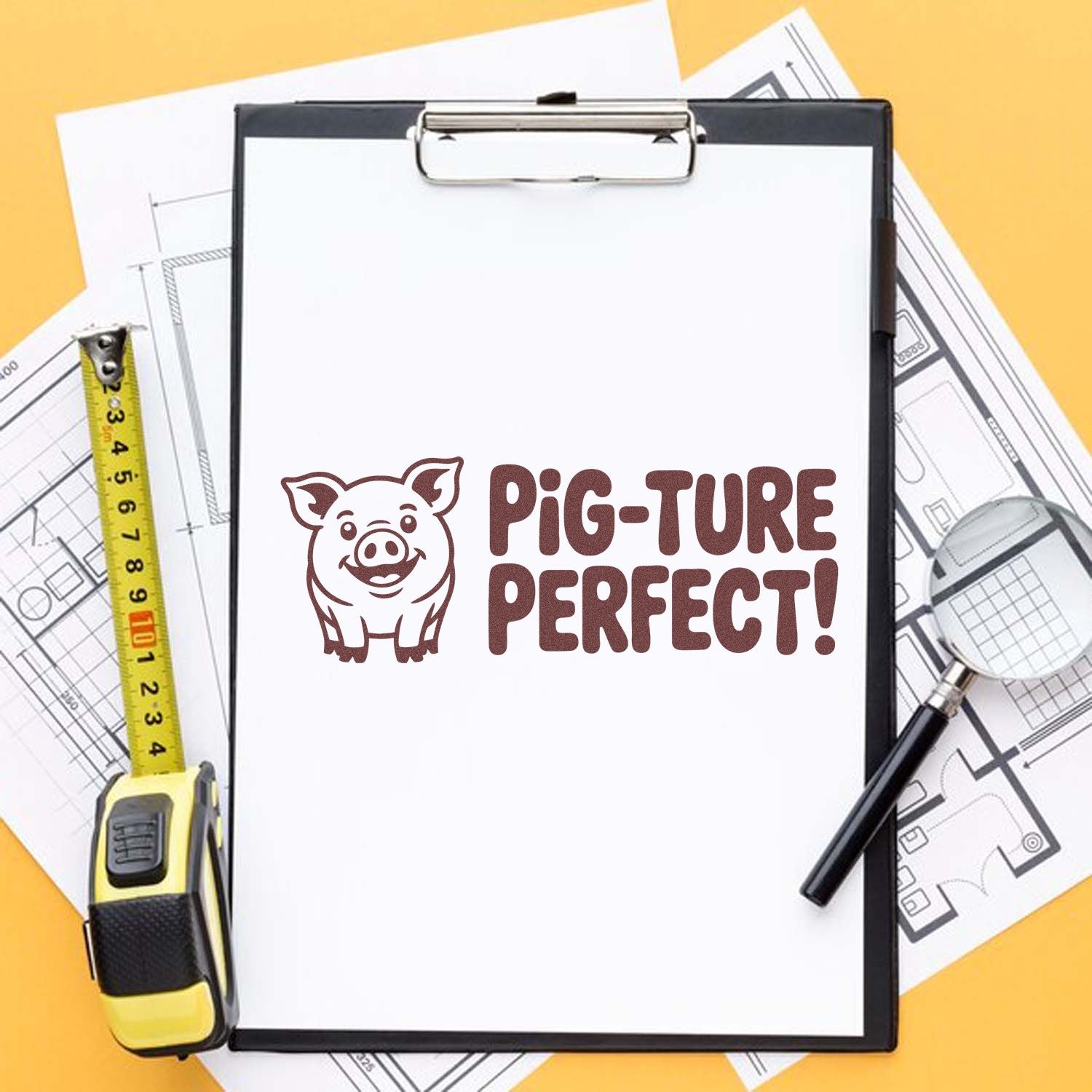 Pig-Ture Perfect pig stamp on white clipboard, with yellow tape measure and blueprint plans on an orange background.