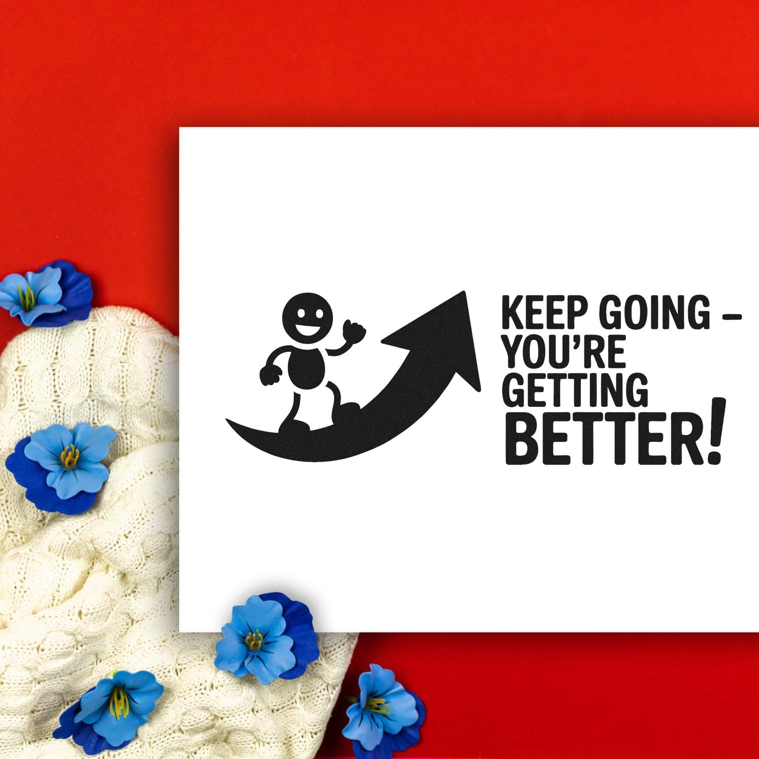 Black motivational stamp and seal reading Keep goingyoure getting better! with upward arrow on white card, red background.