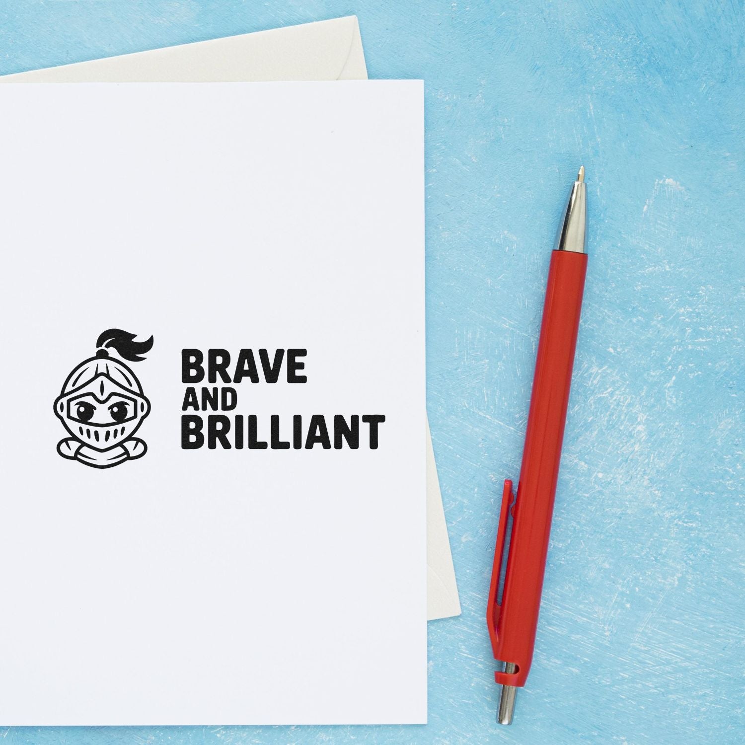 White stamp and seal card with black knight logo and Brave and Brilliant text, beside a red pen on blue background.