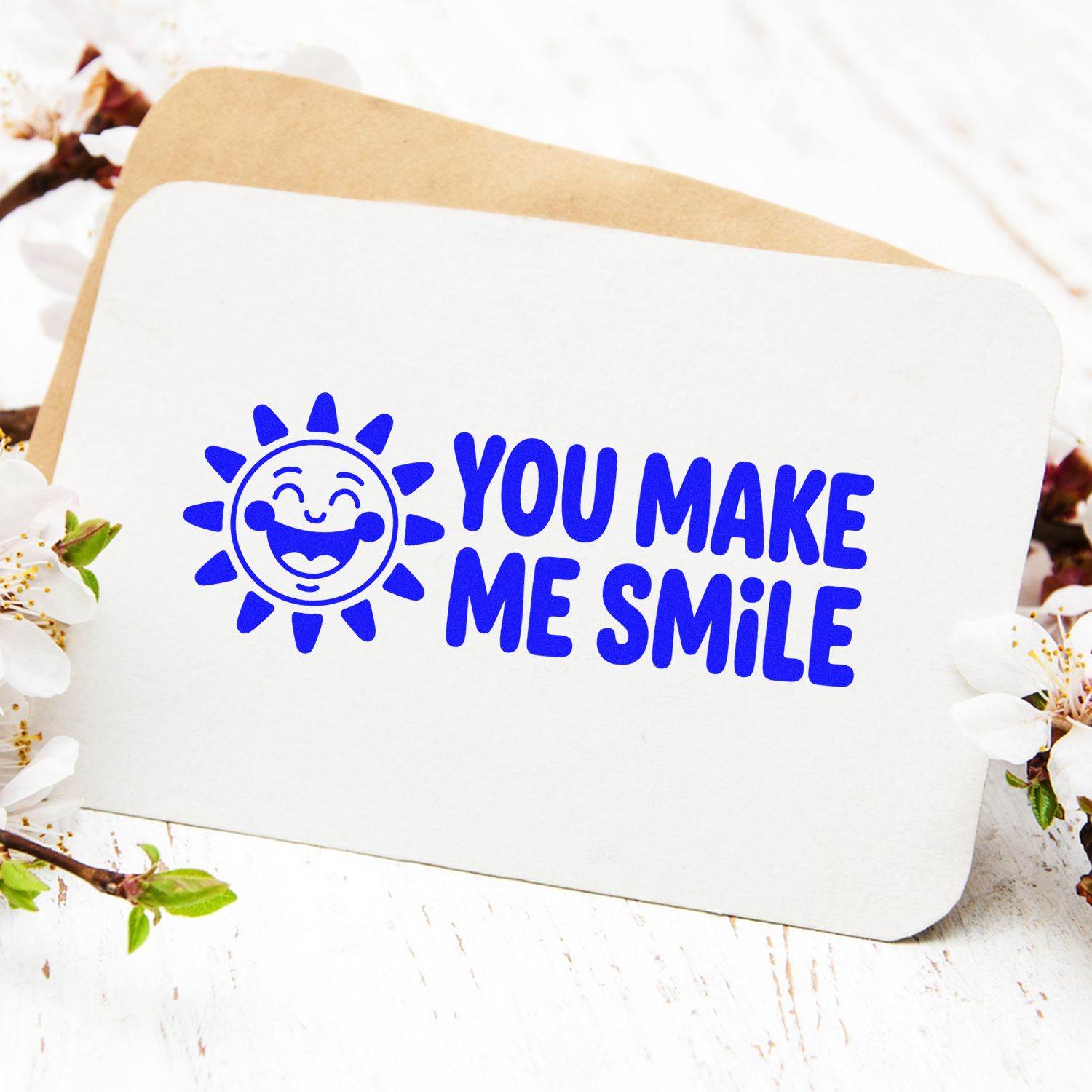 Blue You Make Me Smile stamp and seal with smiling sun icon on white card over tan envelope.