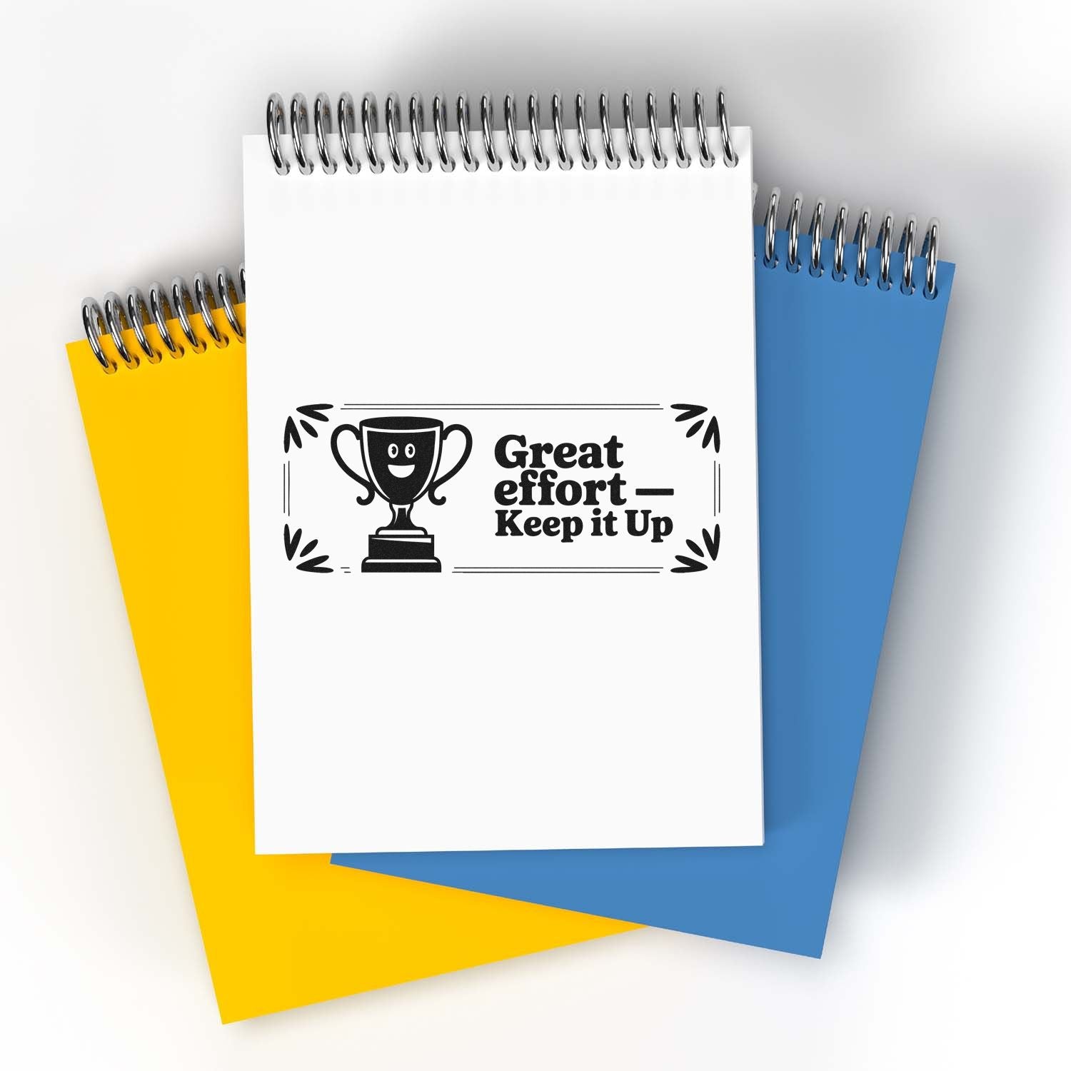 Spiral notepads in white, yellow and blue with a trophy stamp seal reading Great effortKeep it Up.