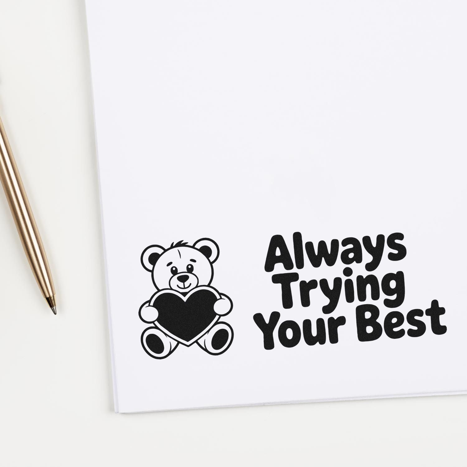 Black bear stamp seal holding a heart with bold black text Always Trying Your Best on white paper.