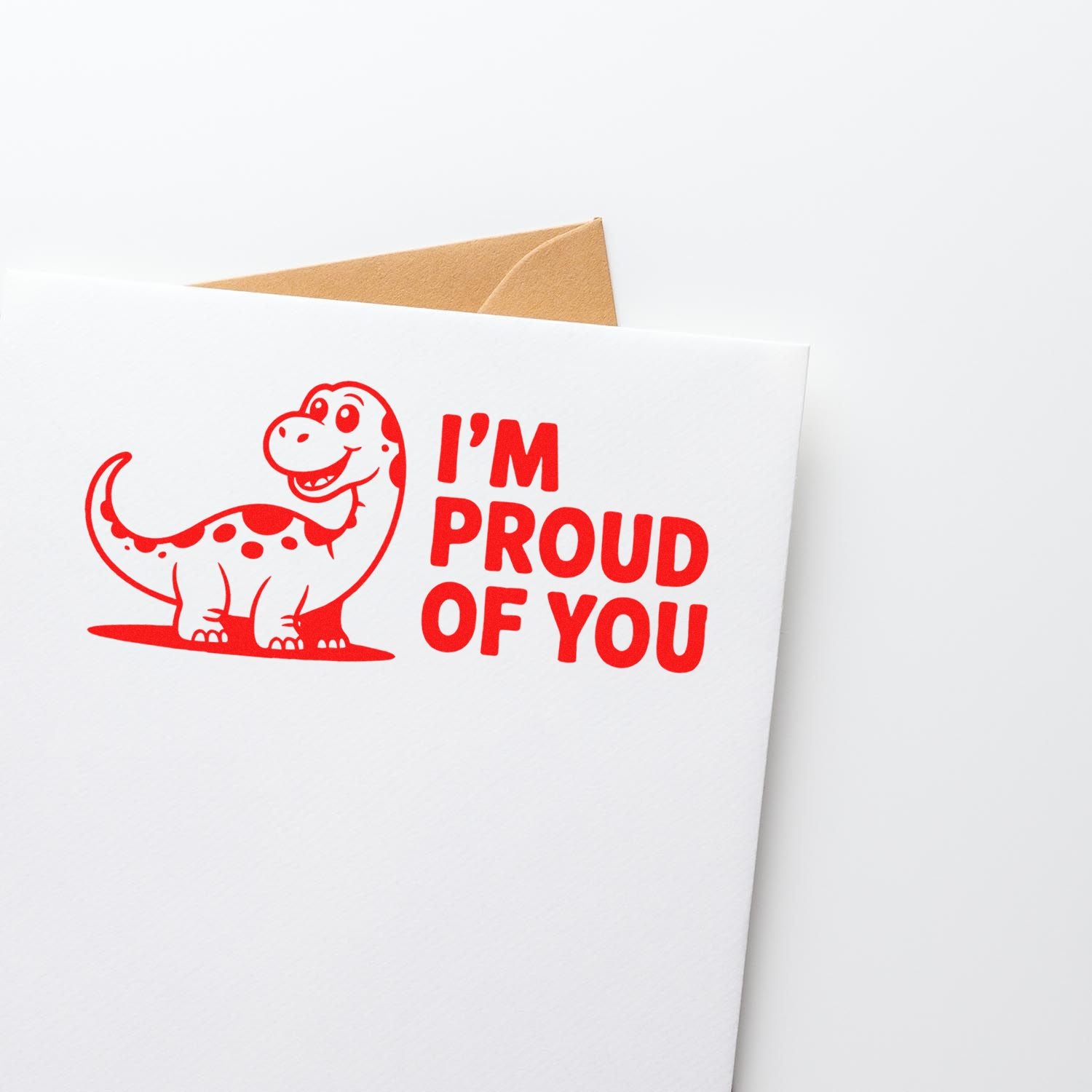 Red dinosaur stamp seal reading Im Proud of You on a white card, with a brown envelope.
