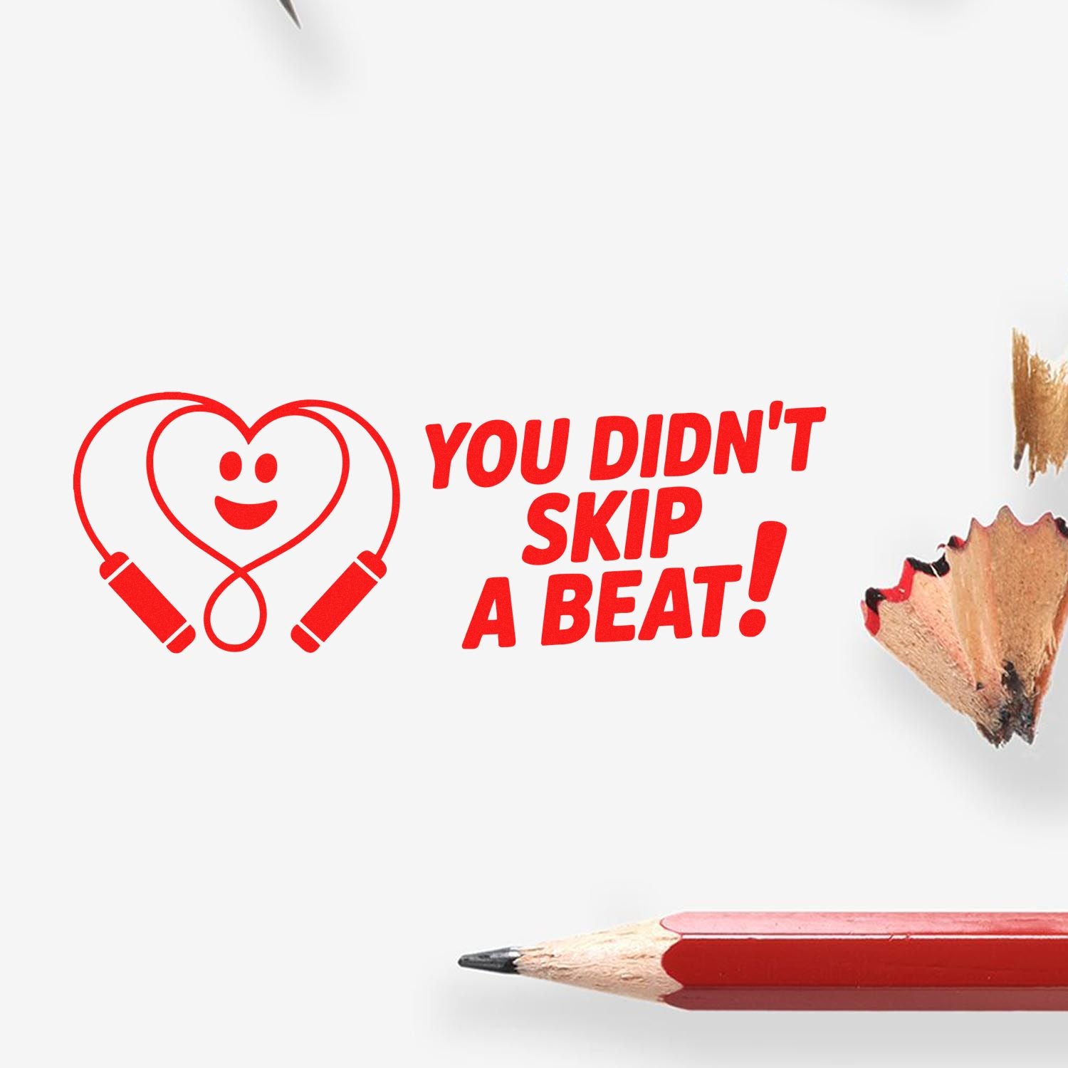 Red heart-shaped stamp seal with smiley and YOU DIDNT SKIP A BEAT! beside a red pencil on white background.