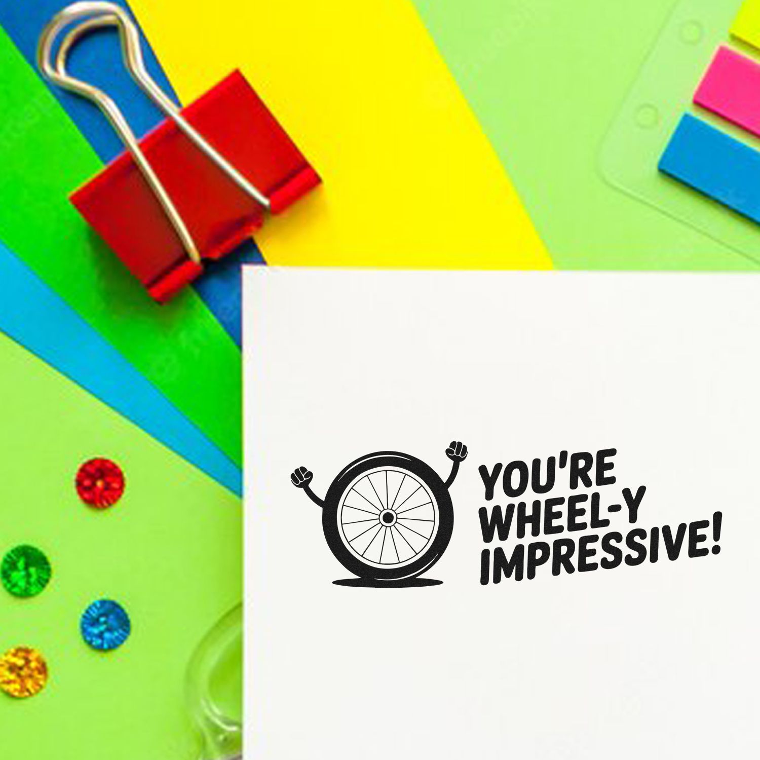 Colorful stationery with red binder clip and custom stamp and seal reading "You're wheely impressive!" beside a wheel icon.