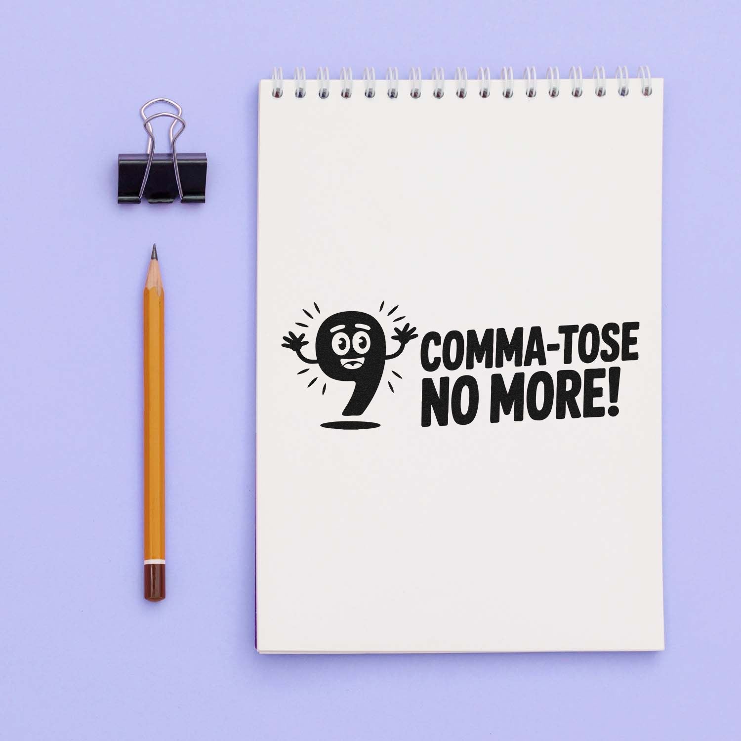 Black custom stamp/seal on a white spiral notebook reading Comma-tose No More! with a cartoon comma on lavender.