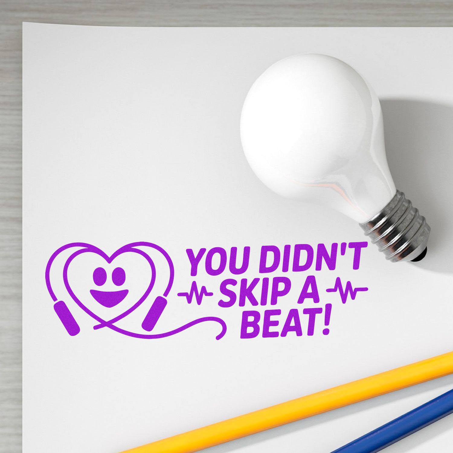 Purple custom stamp and seal design with heart-beat graphic, white lightbulb, and text You didnt skip a beat!