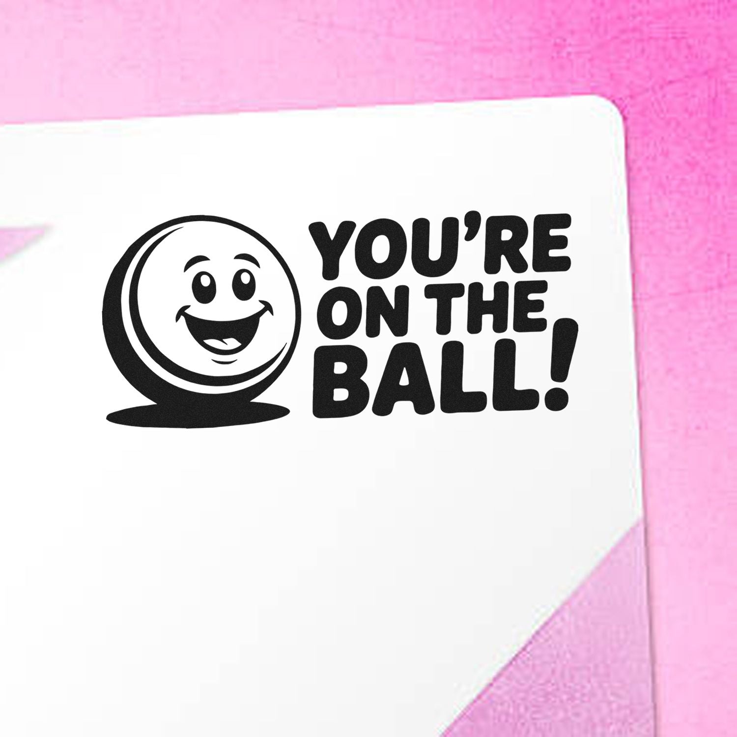 Black Youre on the Ball! stamp and seal design with a smiling ball icon on a white card against a pink background.