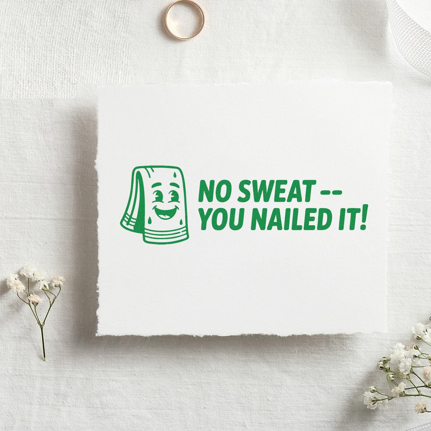 Green rubber stamp seal on white paper with smiling towel mascot and No Sweat -- You Nailed It! text.