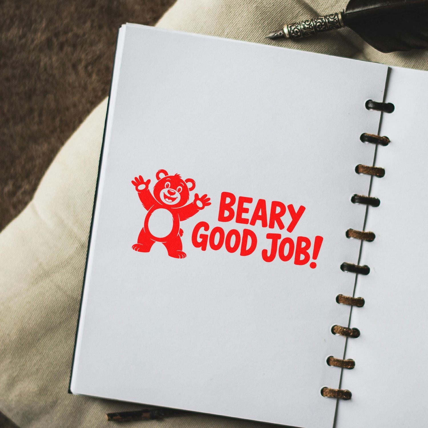 Red bear stamp seal with BEARY GOOD JOB! on a white notebook page with black spiral binding.
