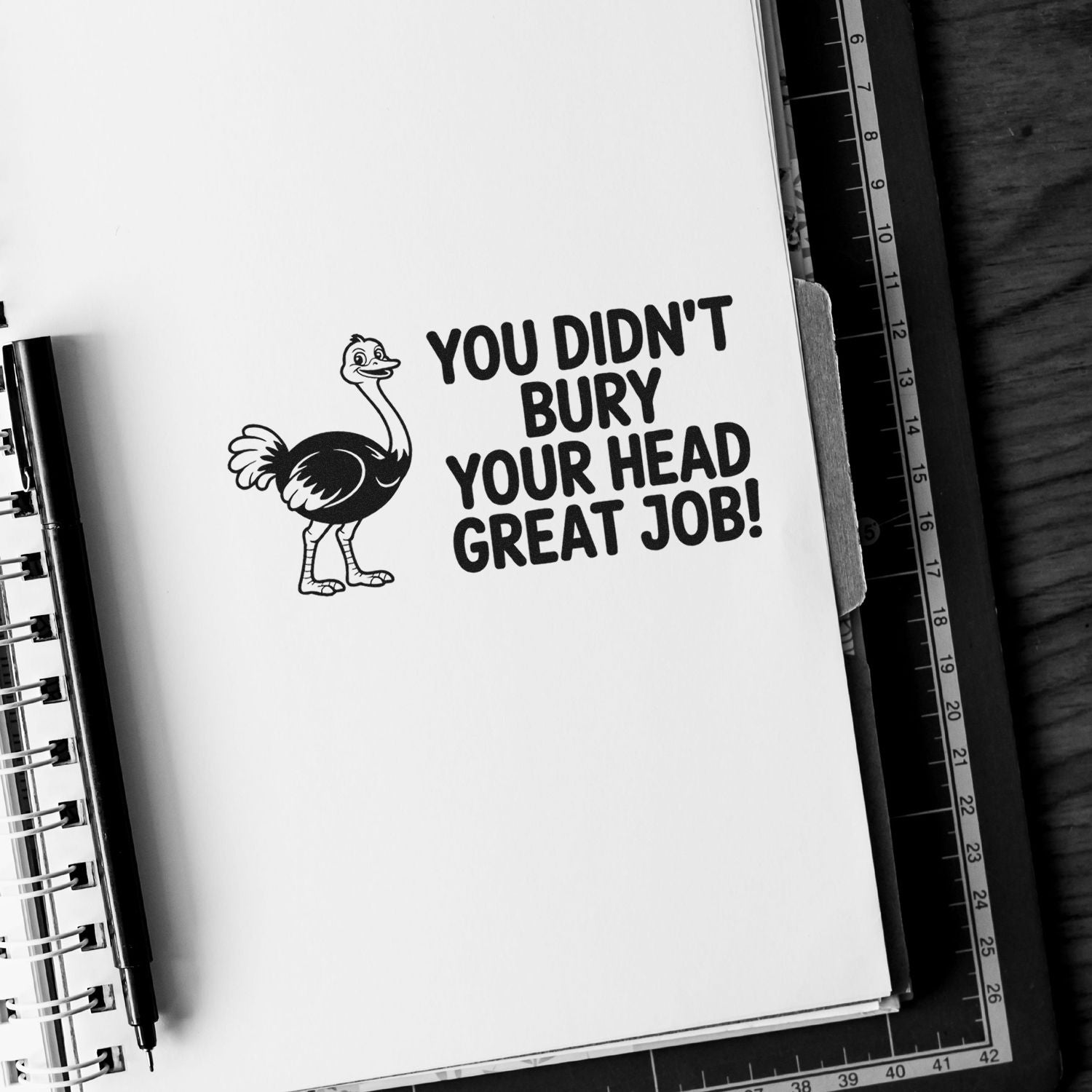 Black rubber stamp seal with an ostrich and bold text, YOU DIDNT BURY YOUR HEAD GREAT JOB! on white paper.