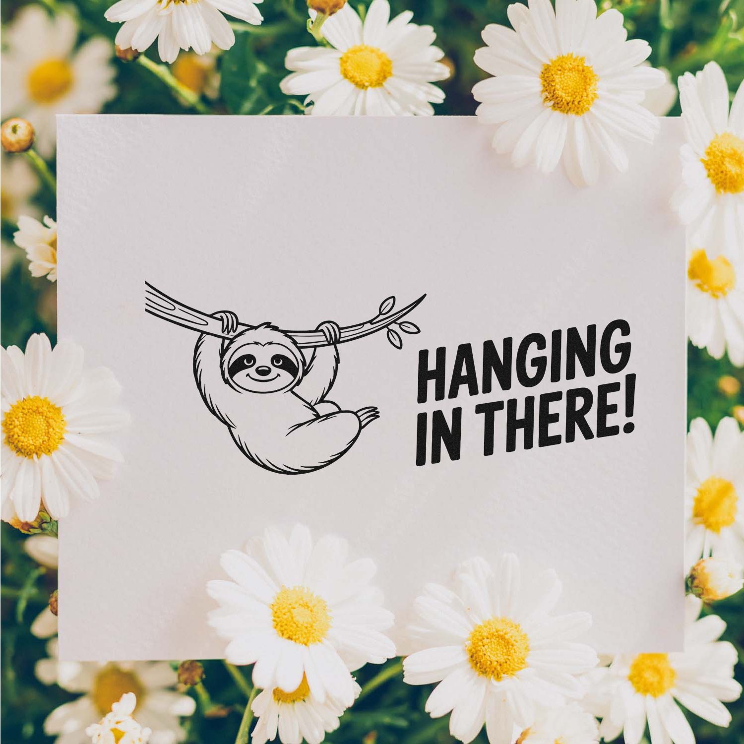 Sloth stamp and seal design with Hanging in There! on a white card, framed by white daisies and yellow centers.