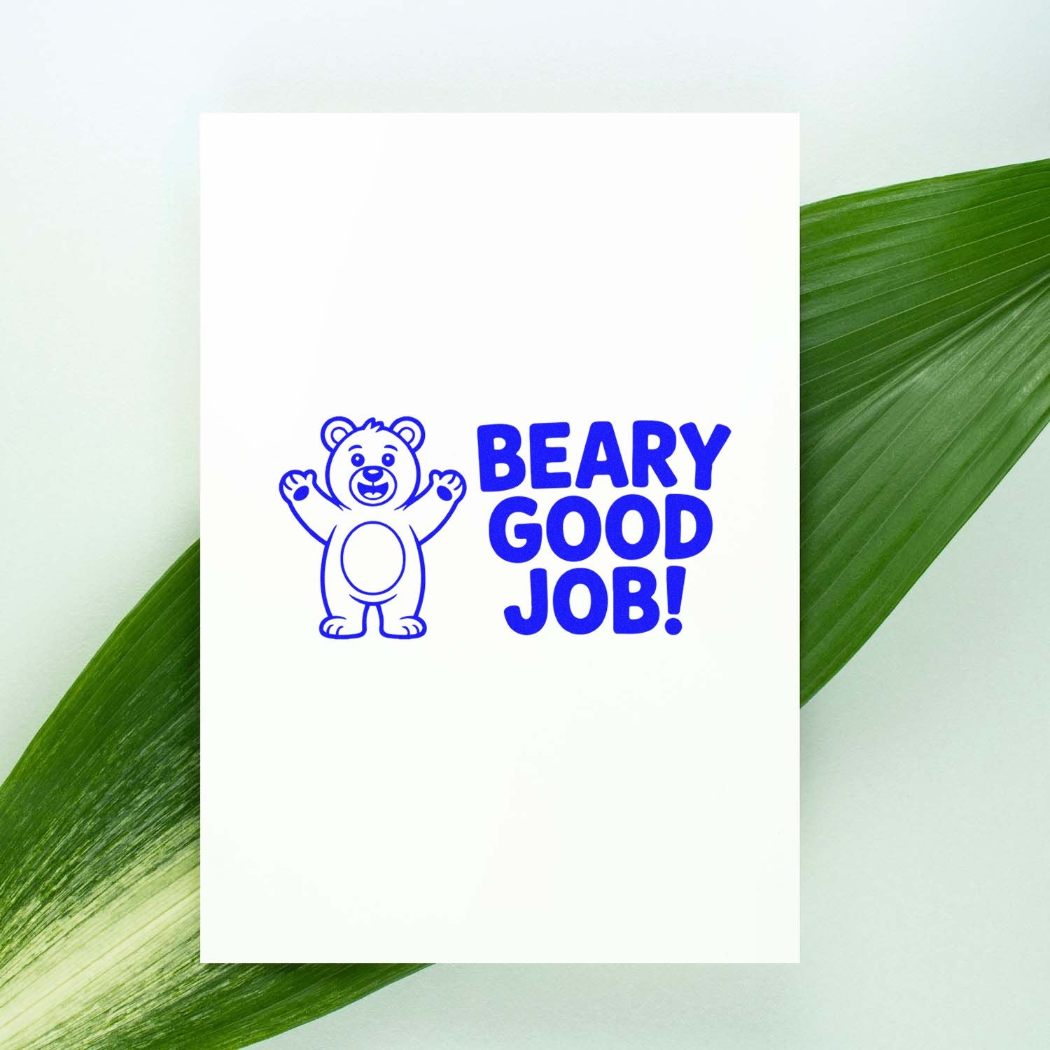 Blue bear stamp and seal reading BEARY GOOD JOB! on a white card with a green leaf background.
