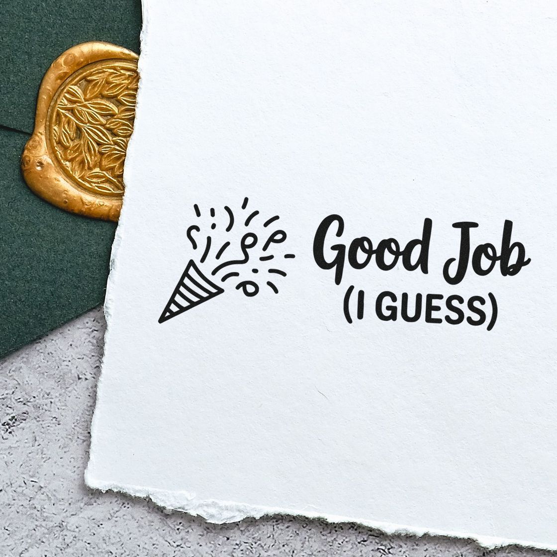 Black Good Job (I Guess) stamp with party popper on white paper, beside a gold embossed seal on dark green background.
