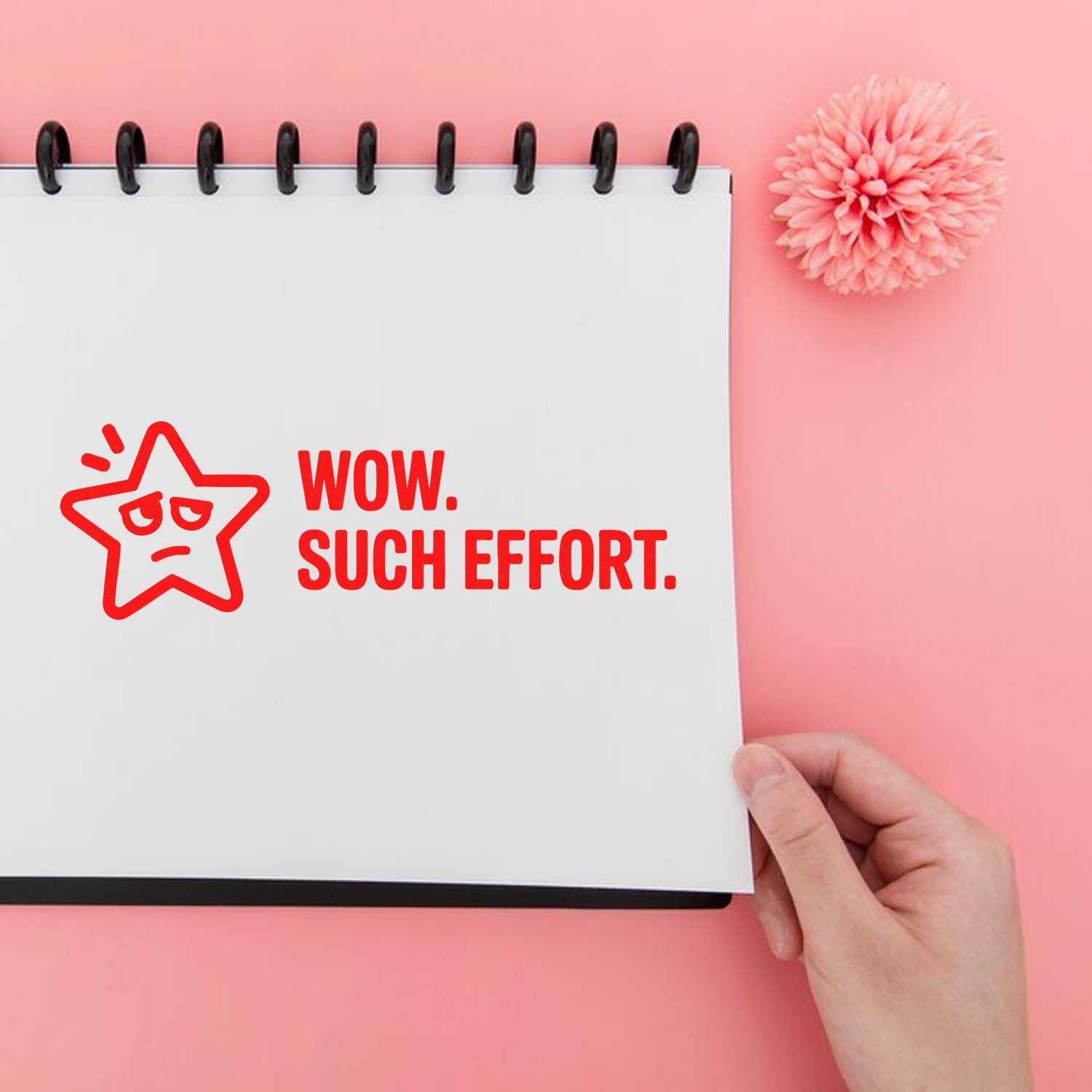 Red rubber stamp reading WOW. SUCH EFFORT. with sad star seal on a white spiral notebook, against a pink background.