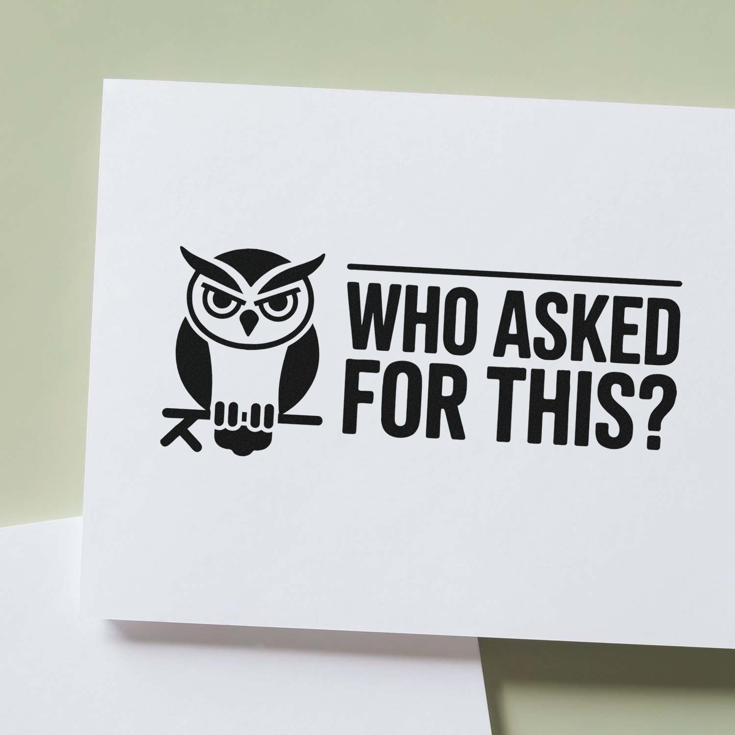 Black owl seal stamp with WHO ASKED FOR THIS? in bold black on white card against pale green background