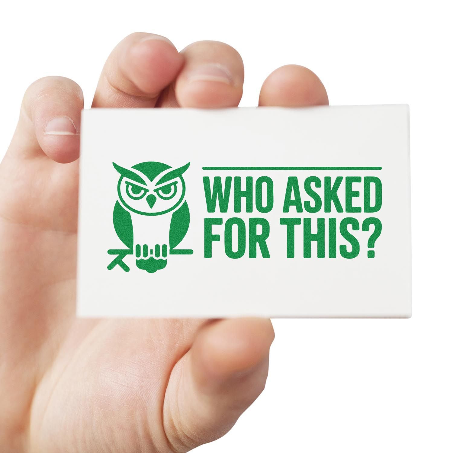 Hand holding white rubber stamp with green owl and WHO ASKED FOR THIS? text, seal product for business use.