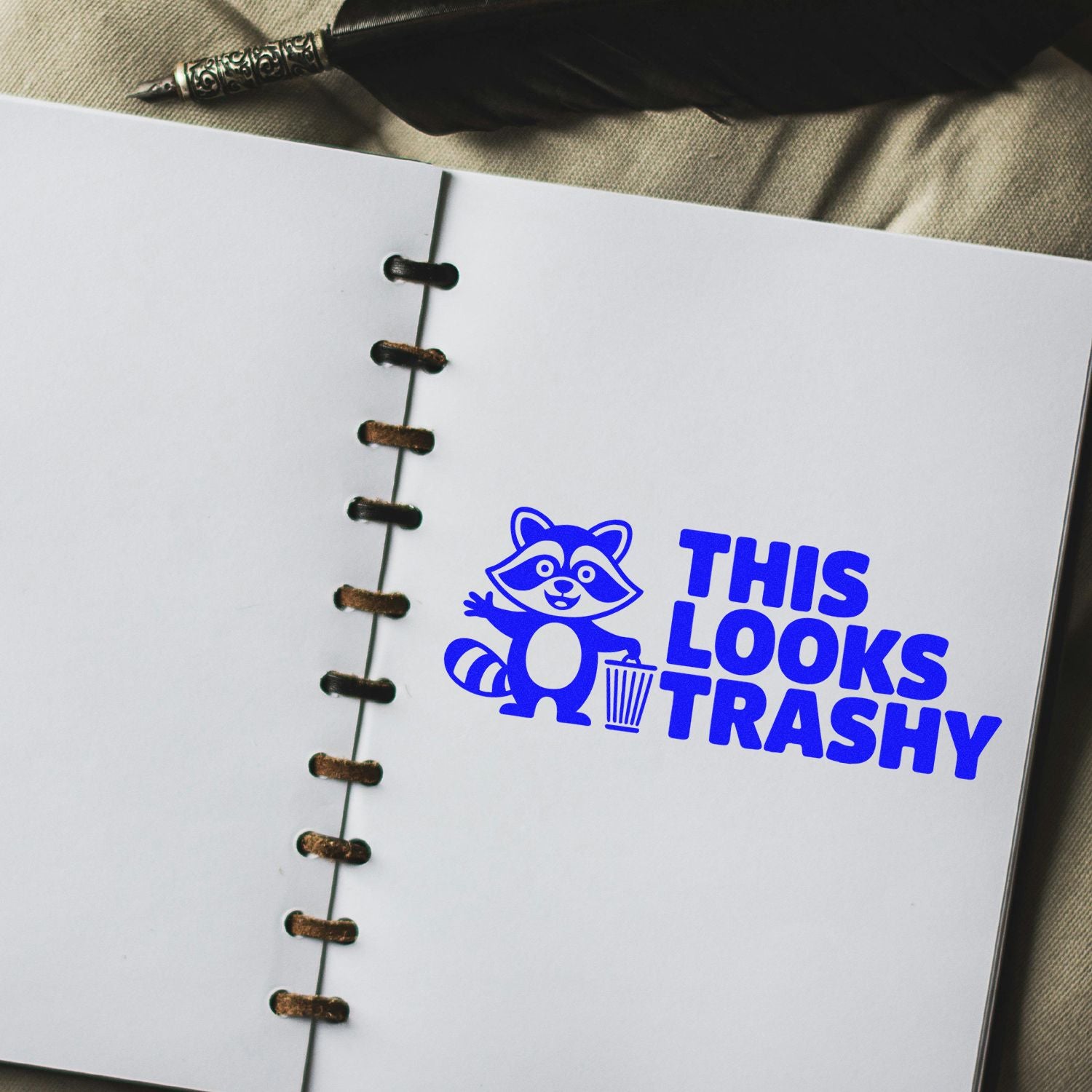 Blue raccoon This Looks Trashy stamp on white spiral notebook page, bold blue custom seal product design.