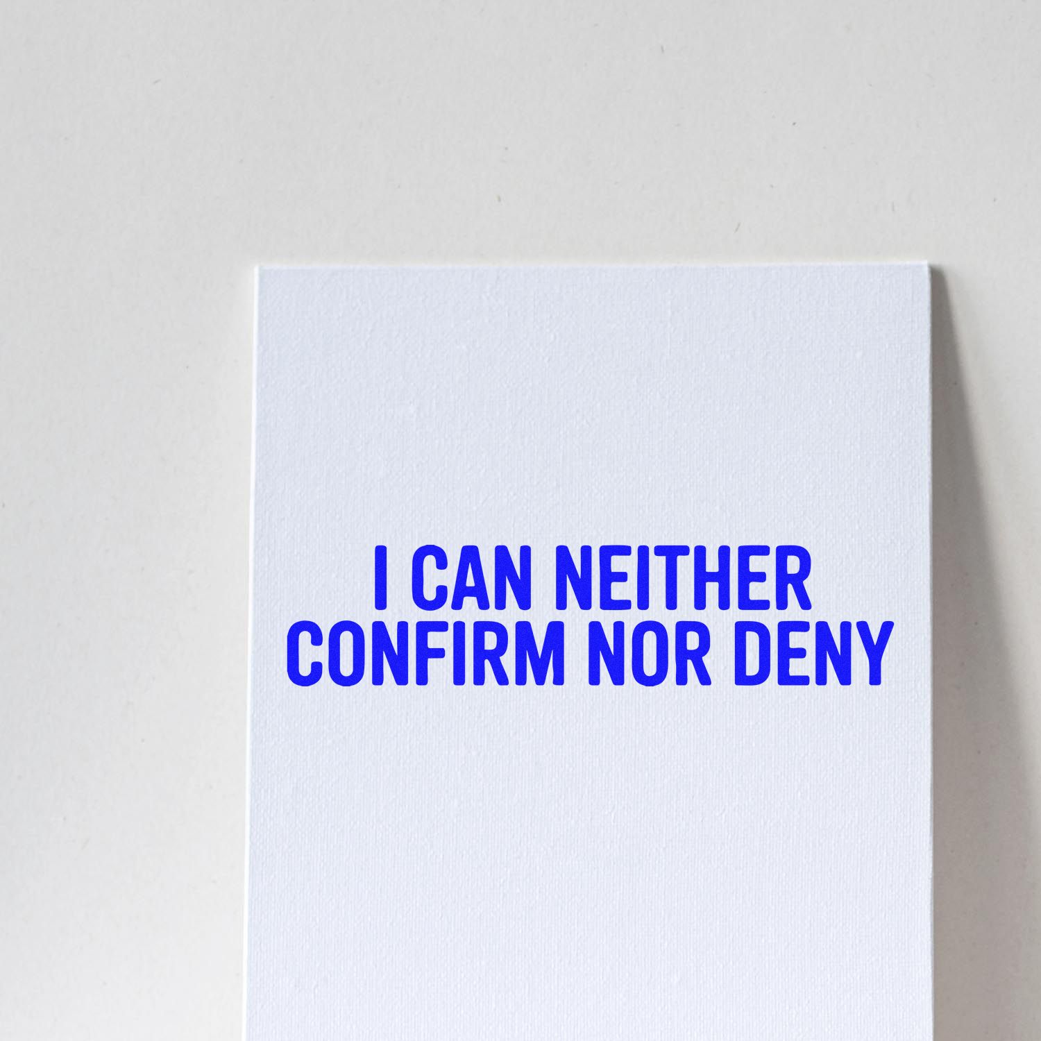 White rubber stamp and seal block with bold blue I CAN NEITHER CONFIRM NOR DENY text.