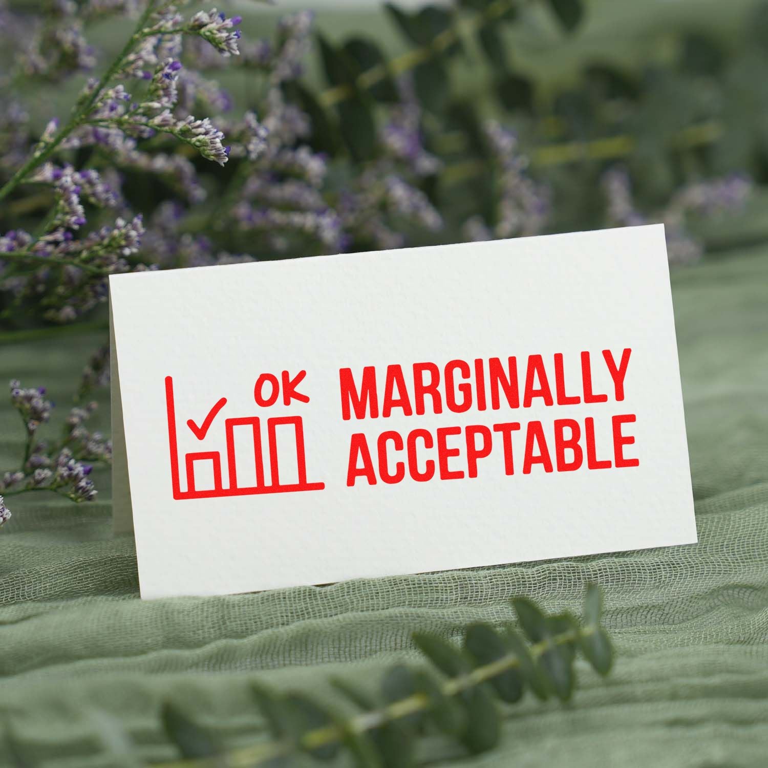White card with red seal-style stamp reading Marginally Acceptable, plus checkmark and bar chart icon, on soft green floral background.