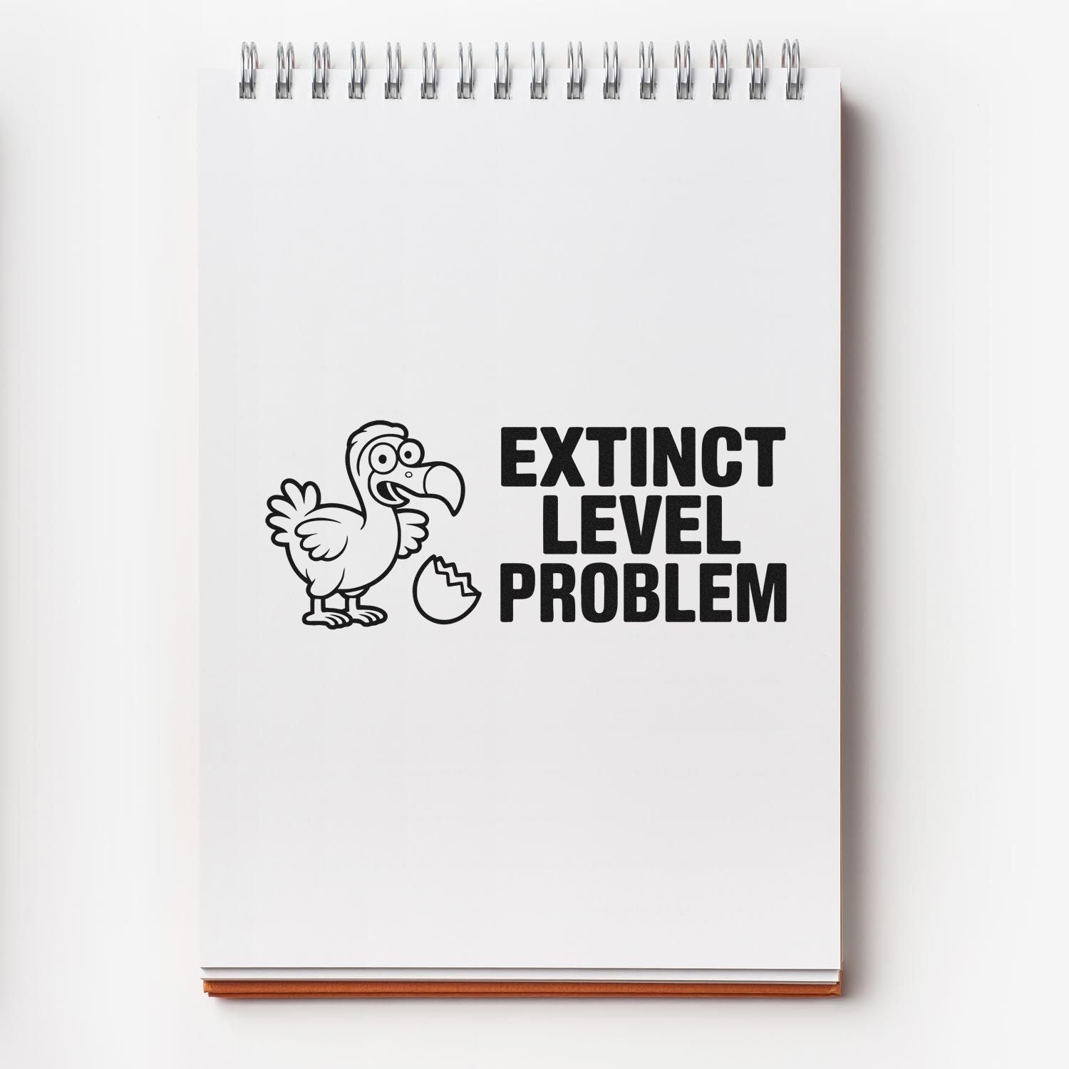Black rubber stamp design on white spiral notebook, featuring cartoon dodo and bold text EXTINCT LEVEL PROBLEM.