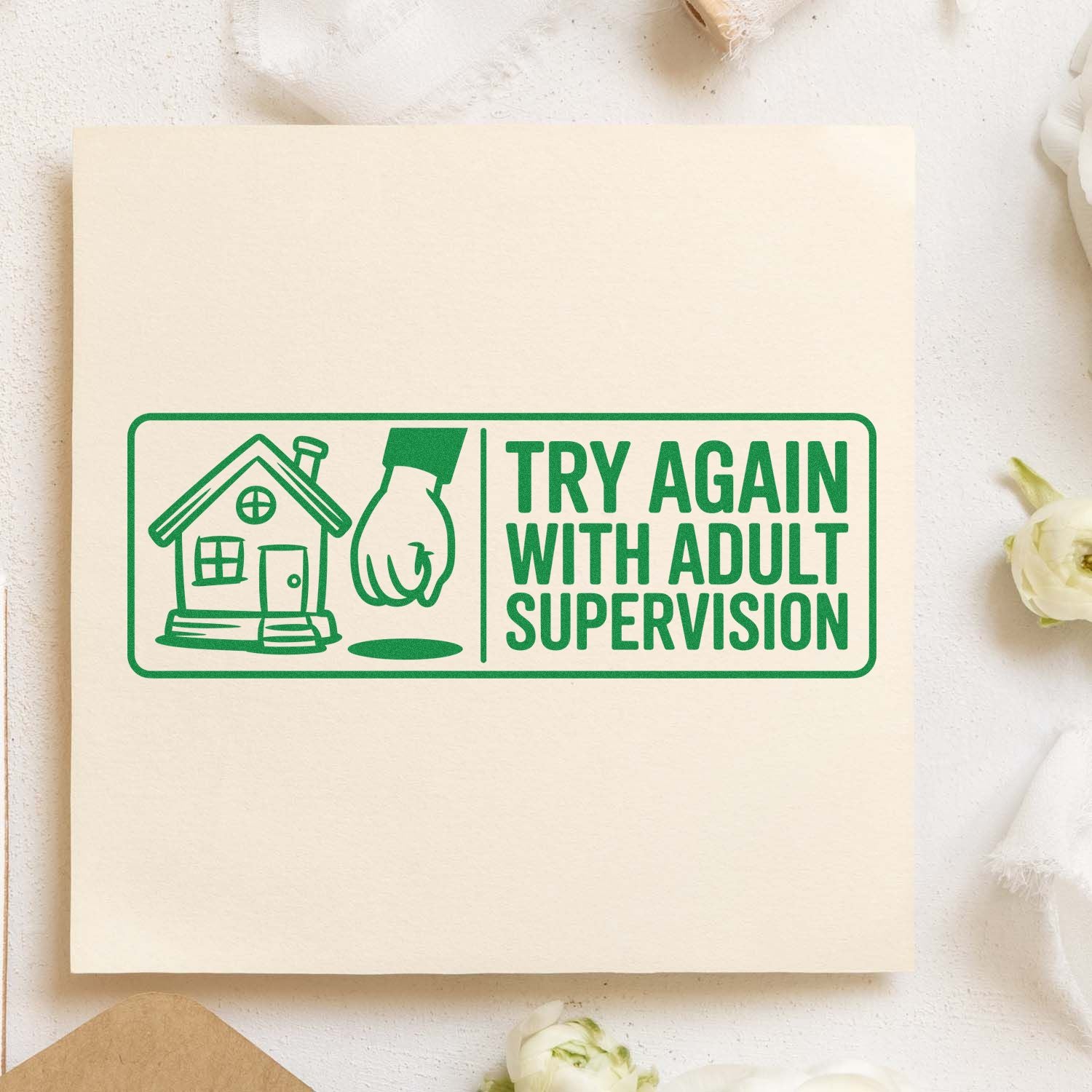 Green rubber stamp seal reading Try Again With Adult Supervision, with house and hand icon on beige paper.