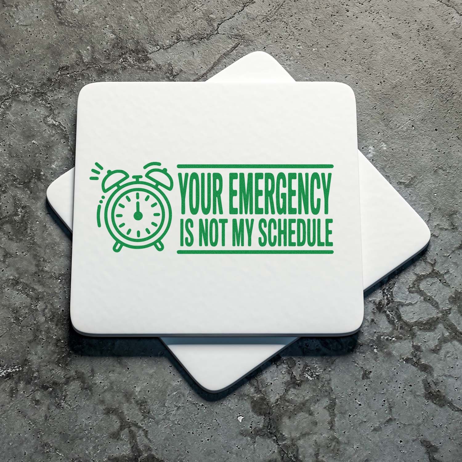 Green stamp and seal set with alarm clock graphic and Your emergency is not my schedule on white tile.