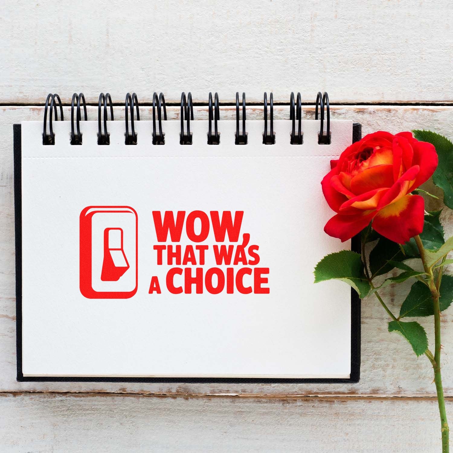 Red rubber stamp and seal reading WOW, THAT WAS A CHOICE on a spiral notepad beside a red rose.