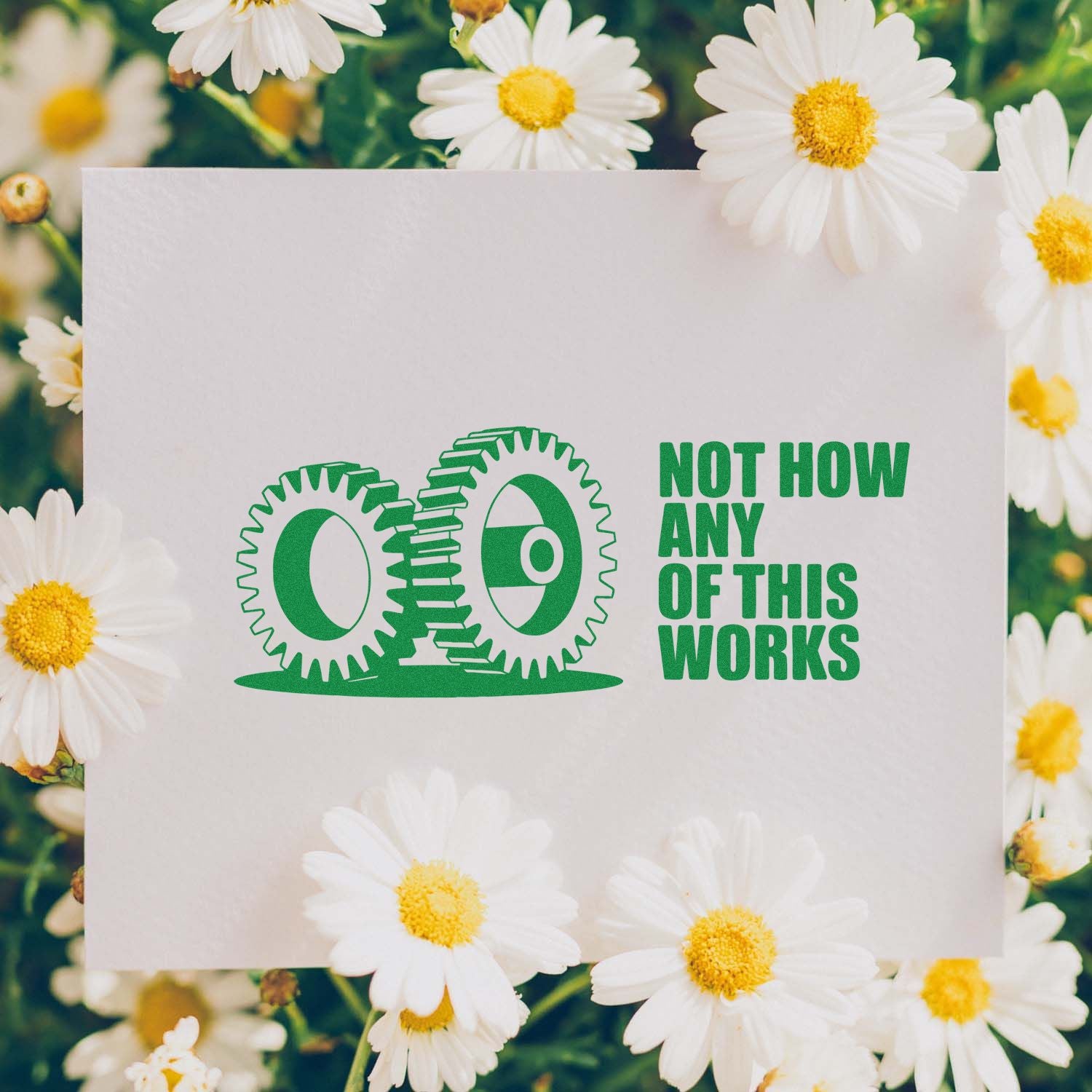 Green rubber stamp seal design reading NOT HOW ANY OF THIS WORKS on white card, framed by white daisies.