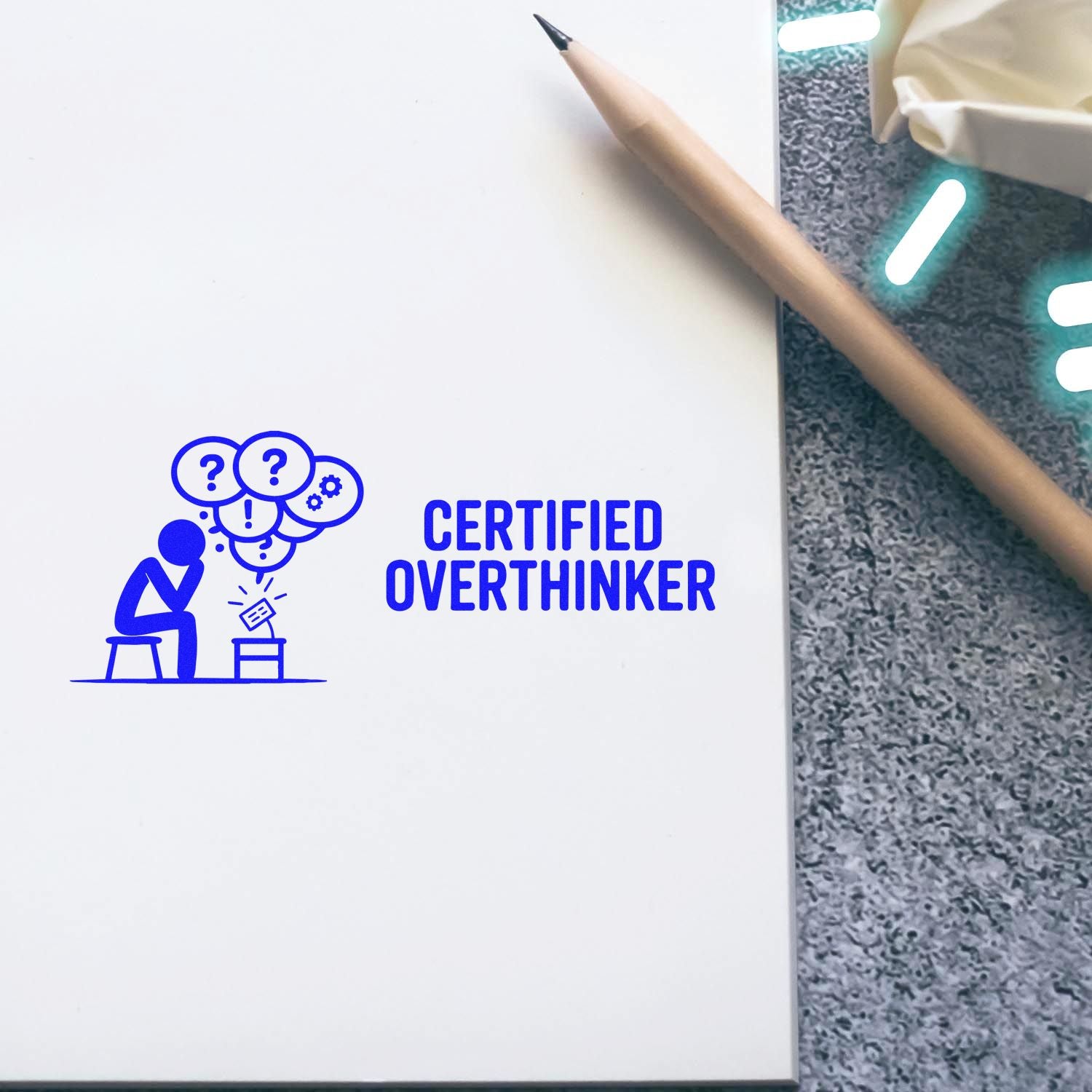 Blue certified overthinker stamp and seal on white notebook beside a pencil, with a thinking figure and question bubbles.