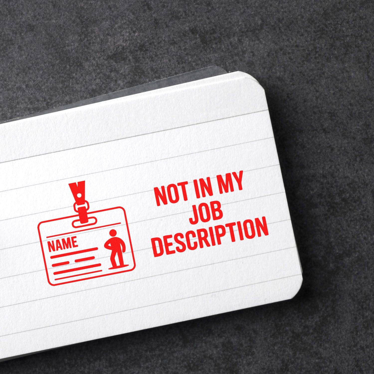 Red stamp-style seal on white lined card, reading Not in My Job Description, with ID badge icon on dark background.
