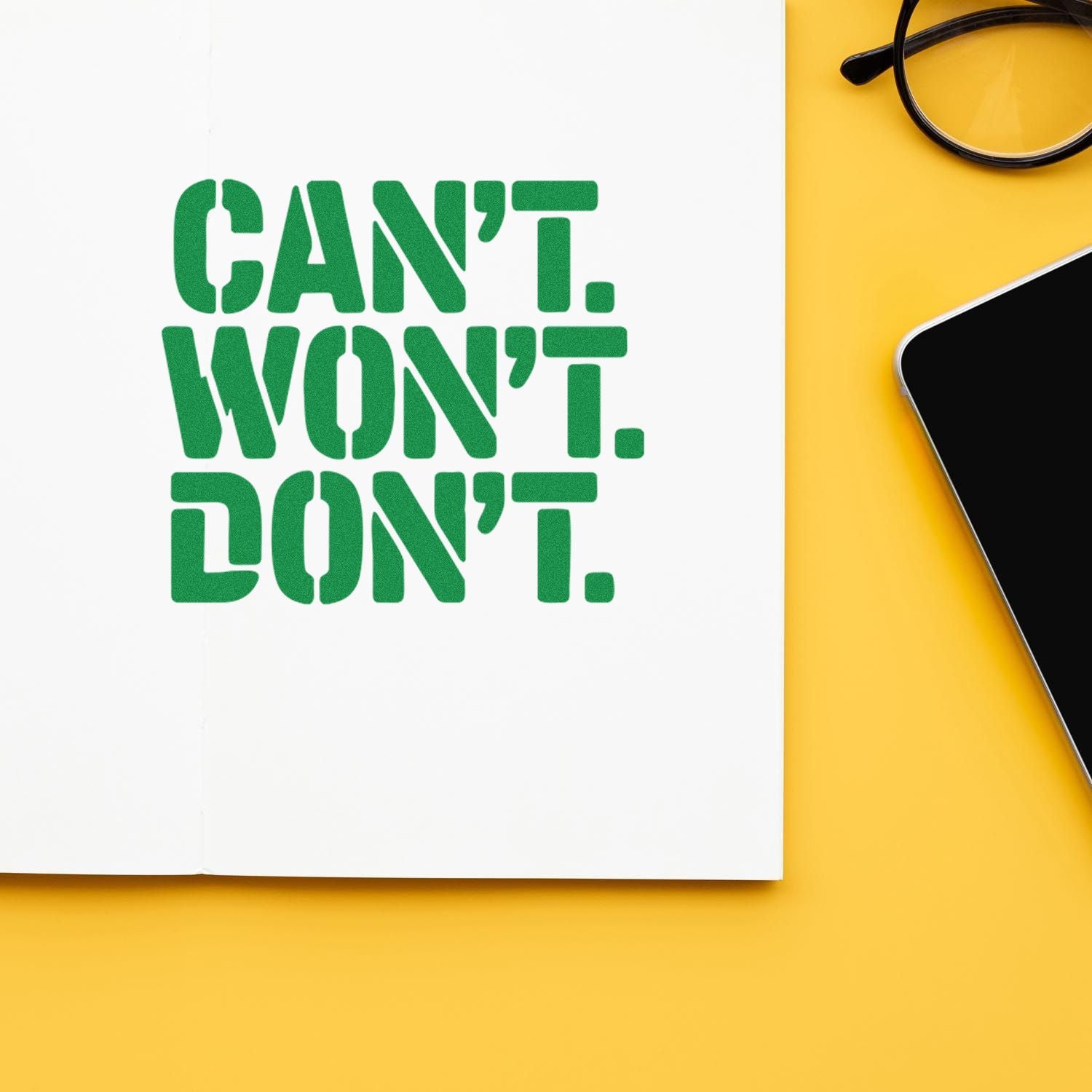 Green stamp-style CANT. WONT. DONT. seal on white paper, beside eyeglasses and a smartphone on yellow.