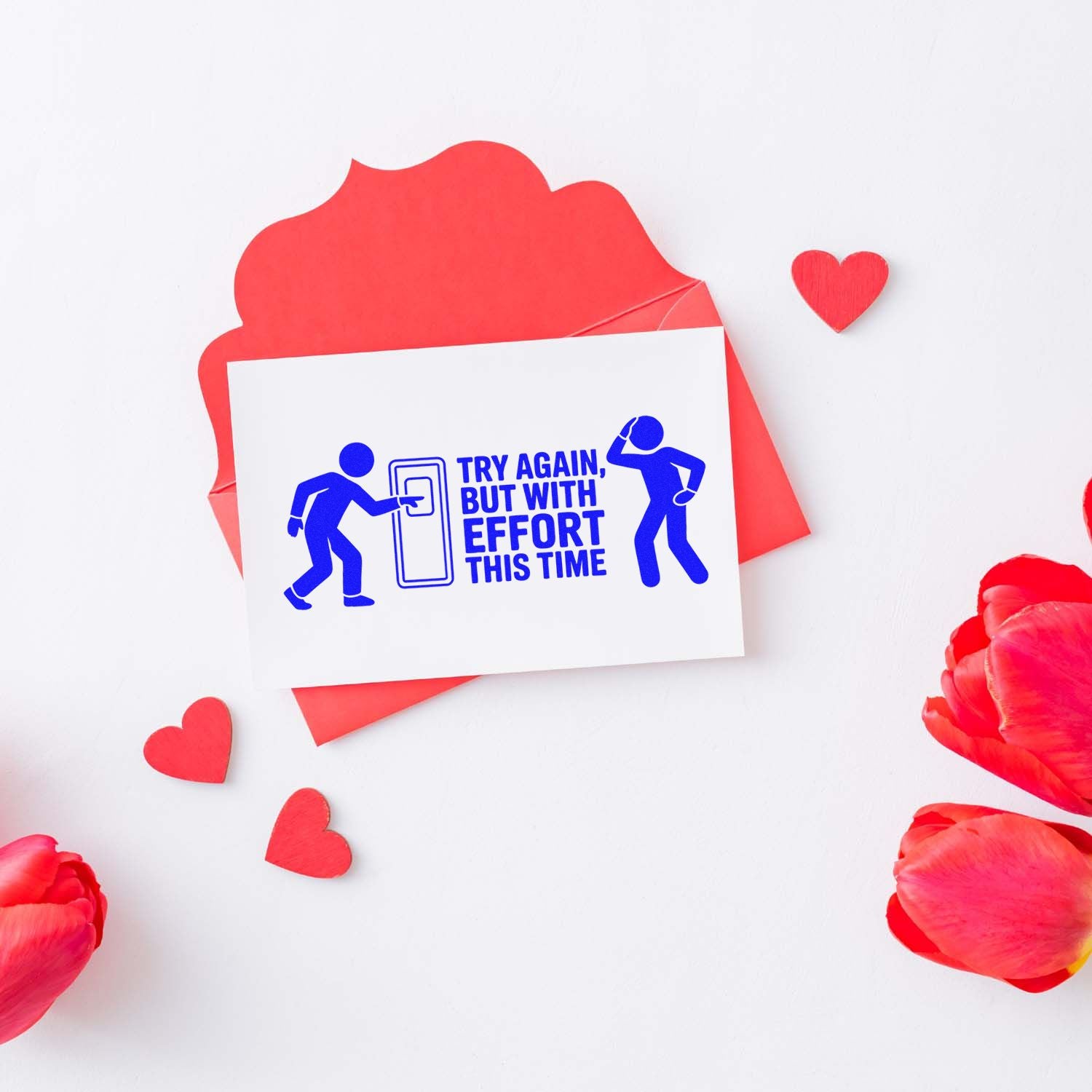 Blue rubber stamp reading Try again, but with effort this time on a red envelope with hearts and pink petals.